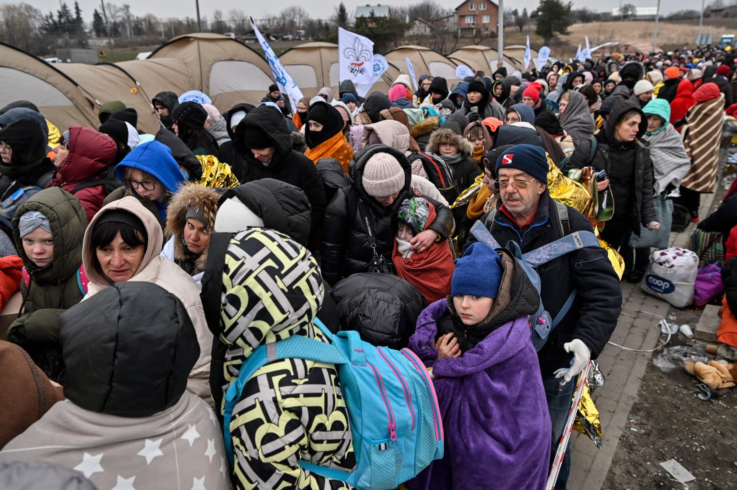 Refugees stand in line in the cold as they wait to be transferred to a train station after crossing the Ukrainian border into Poland, at the Medyka border crossing in Poland, on March 7, 2022. - More than 1.5 million people have fled Ukraine since the start of the Russian invasion, according to the latest UN data on March 6, 2022. (Photo by Louisa GOULIAMAKI / AFP)