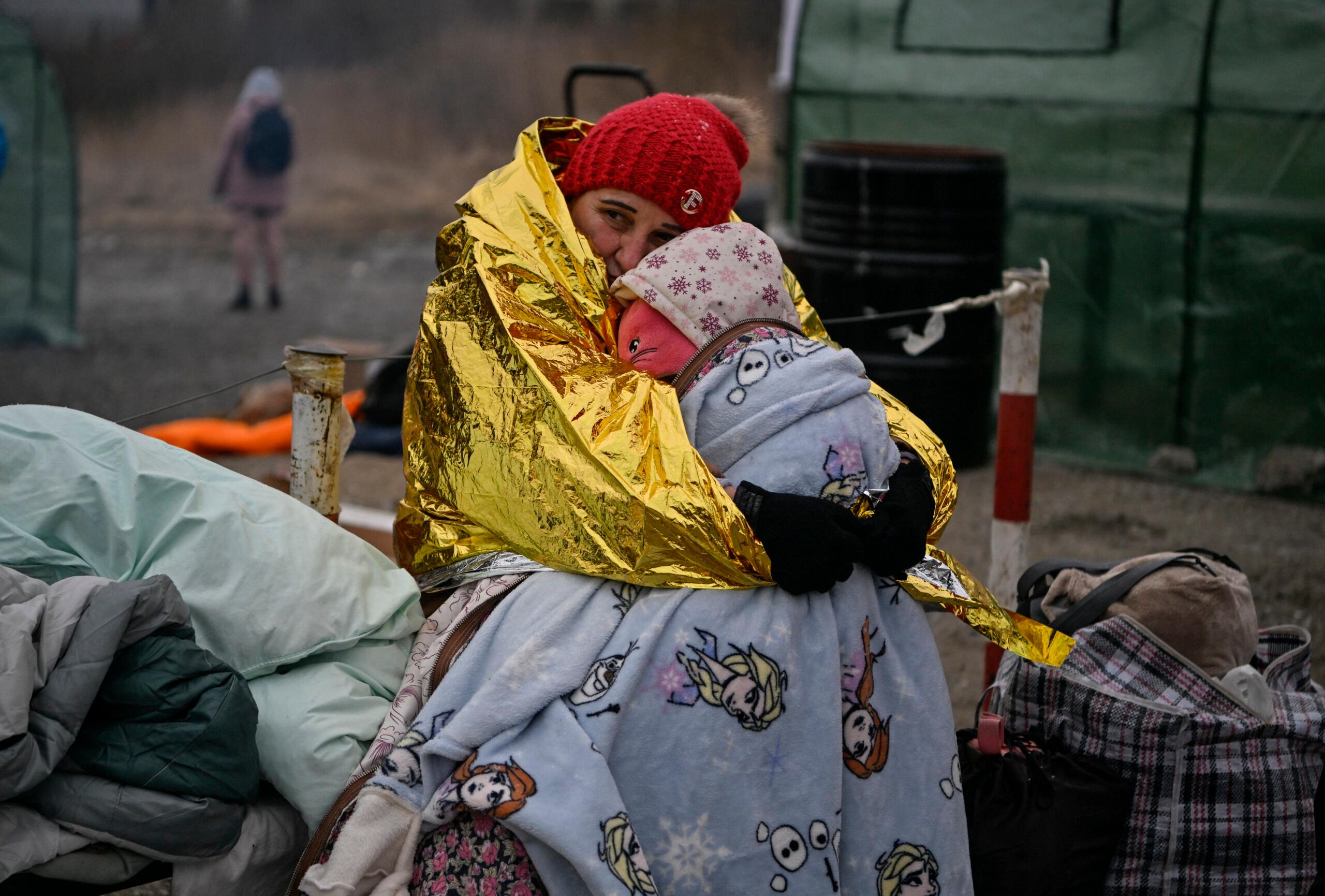 Objęte i przykryte kocem termicznym mata i dziecko, uchodźcy z Ukrainy na polskiej granicy