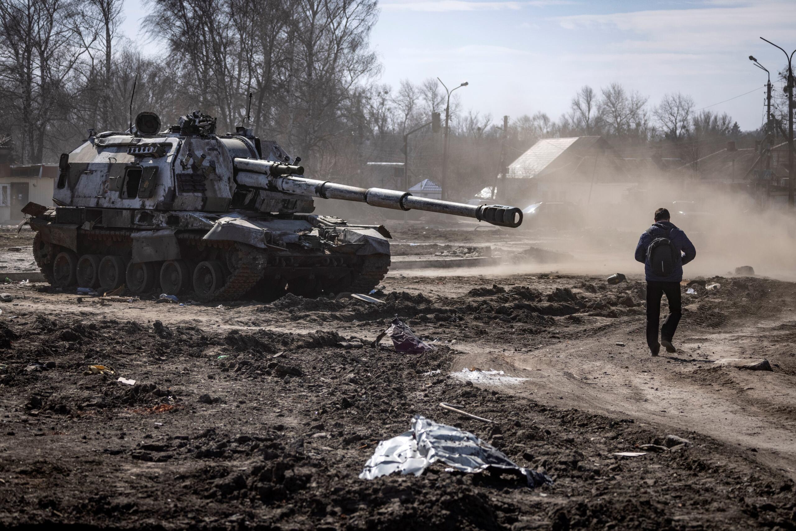 Mieszkaniec przechodzi koło rozpierdolonego w drzazgi rosyjskiego czołgu w Trościancu