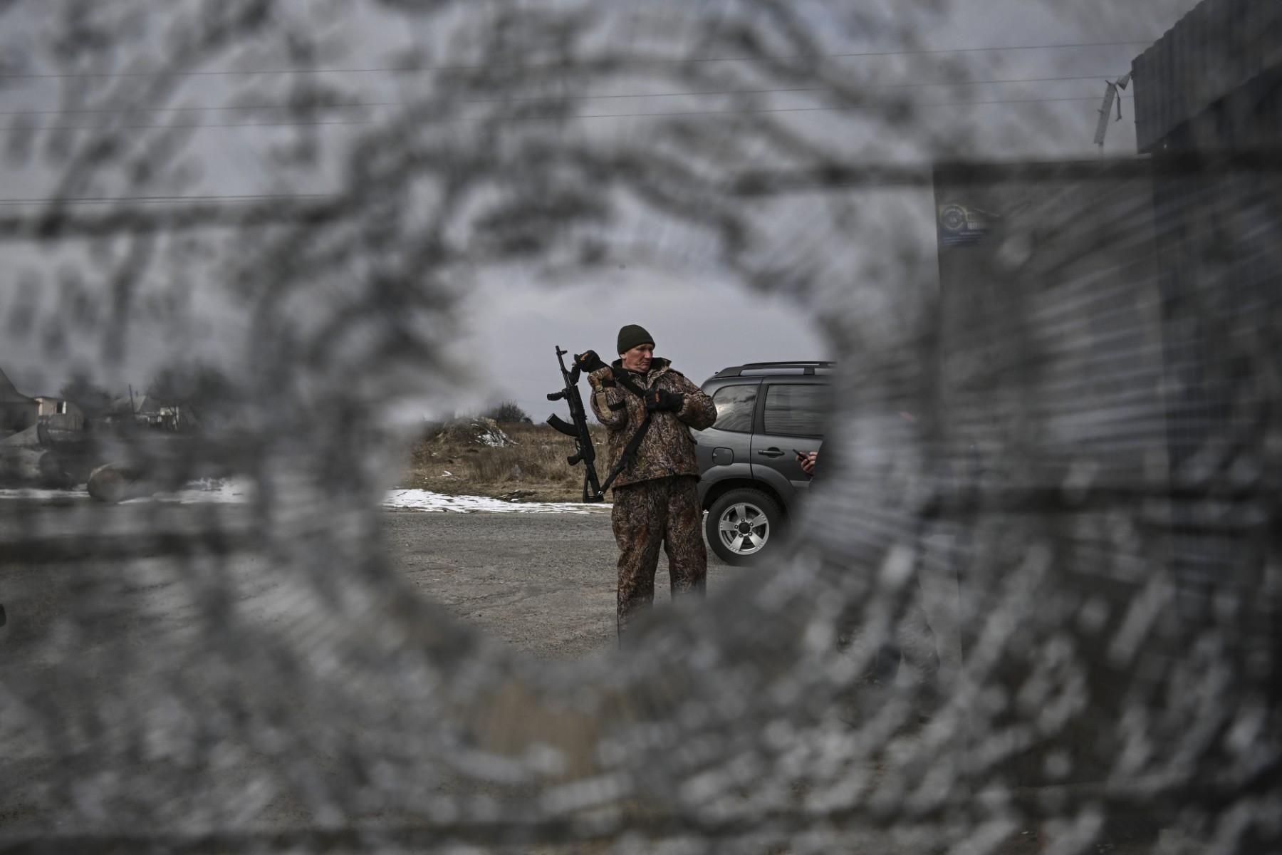 Ukraiński żołnierz widziany przez otwór w zwoju drutu kolczastego