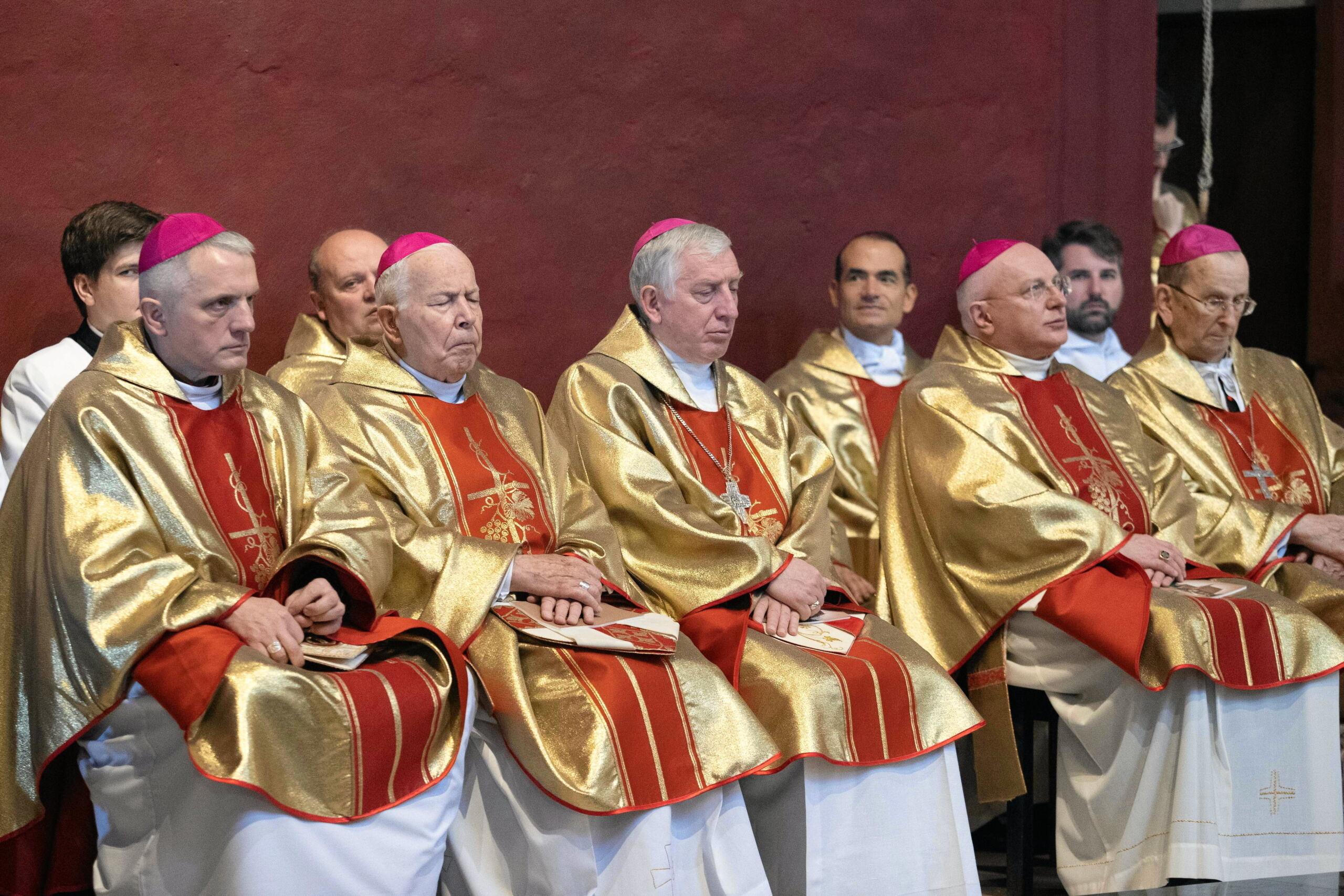 kilku zaspanych biskupów siedzi w odświętnych strojach liturgicznych