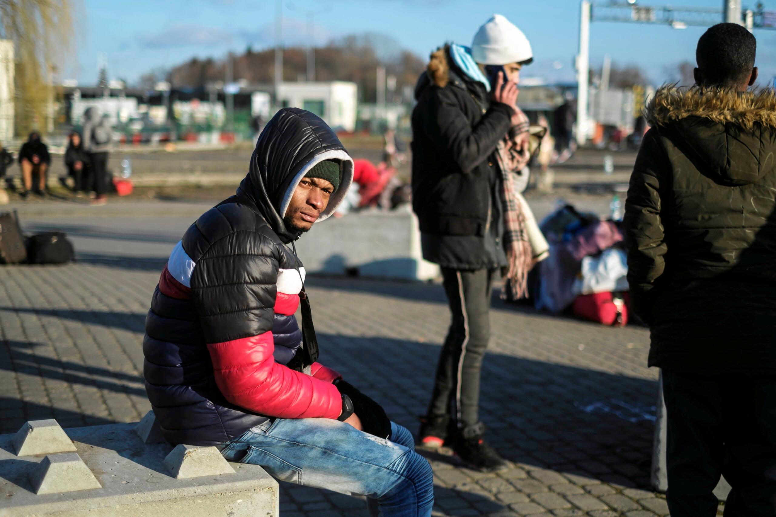 Czarnoskóry uchodźca z Ukrainy siedzi na betonowej barierze