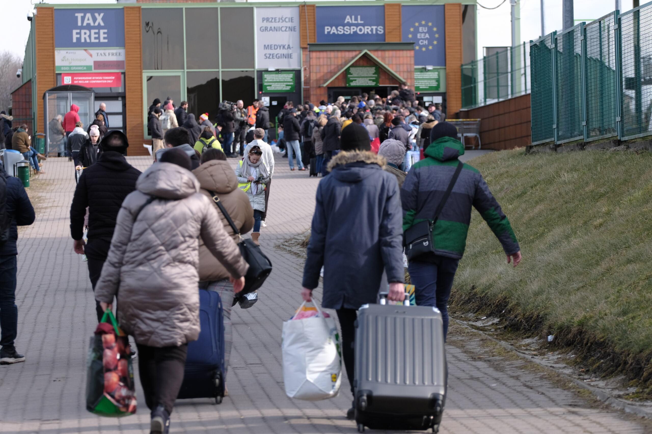 Ludzie z bagażami idą przez przejście graniczne