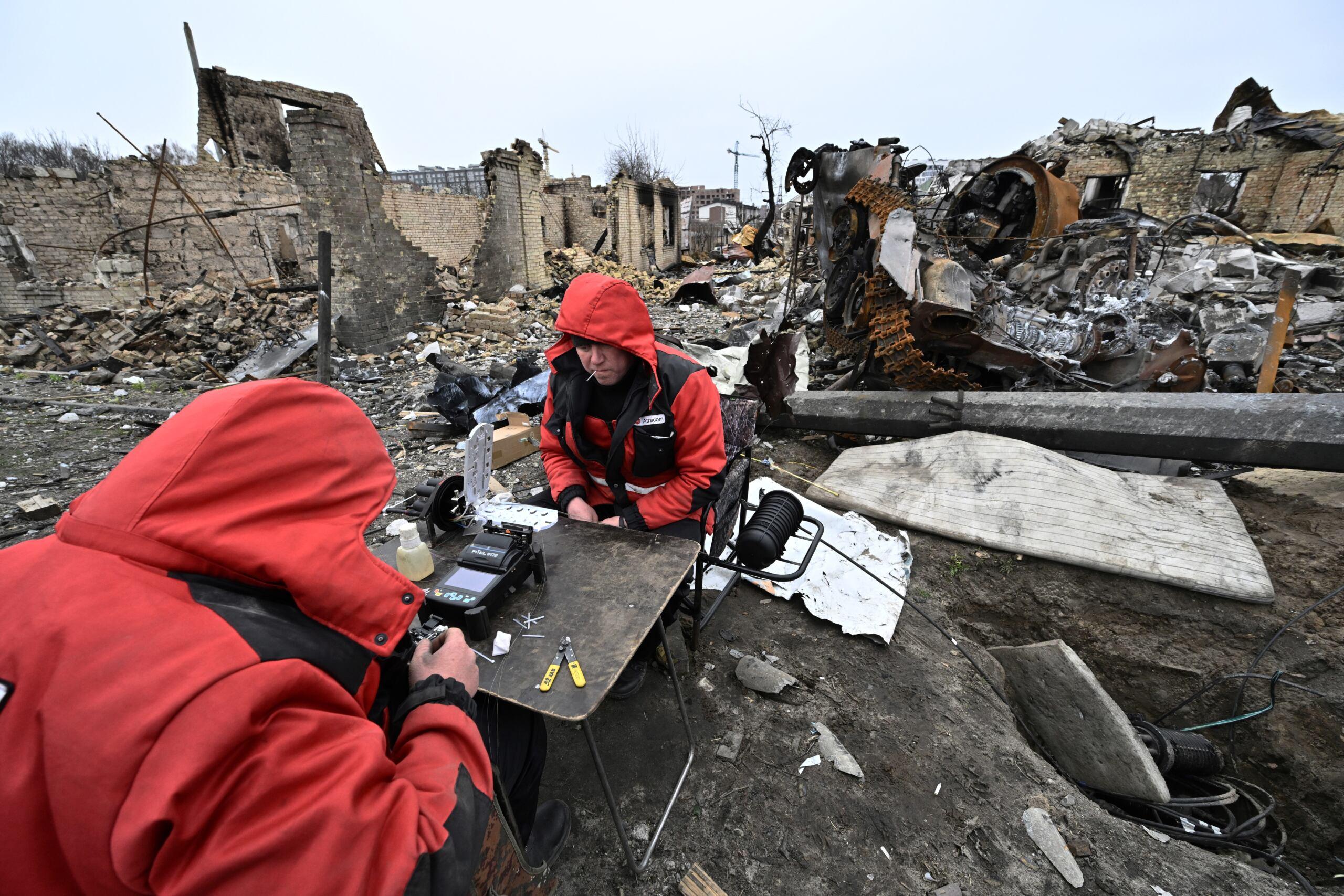 Bucza. Dwóch mężczyzn w czerwonych kurtkach pracuje z urządzeniami elektronicznymi na ruinach