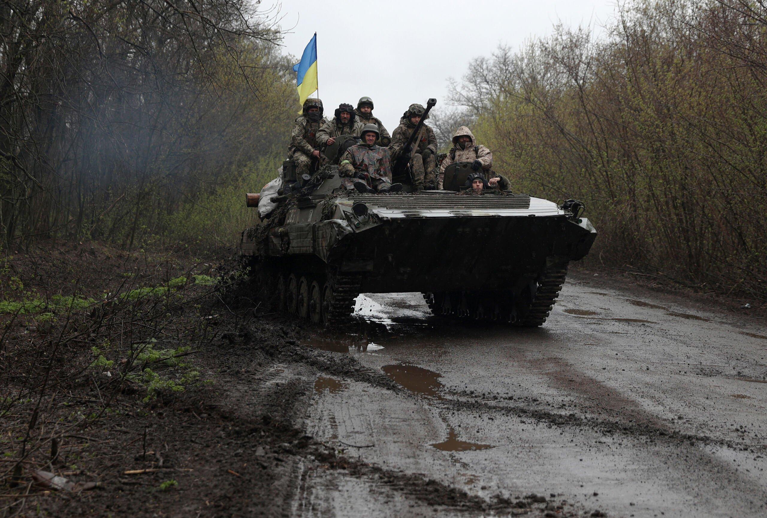 Żołnierze jadą na transporterze opancerzonym z ukraińską flagą