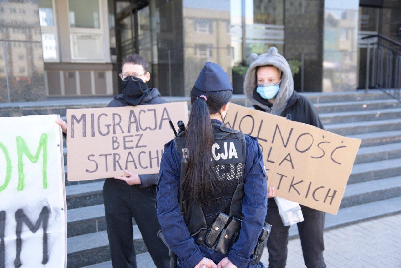 Trzy osoby z transparentami solidaryzującymi się z migrantami