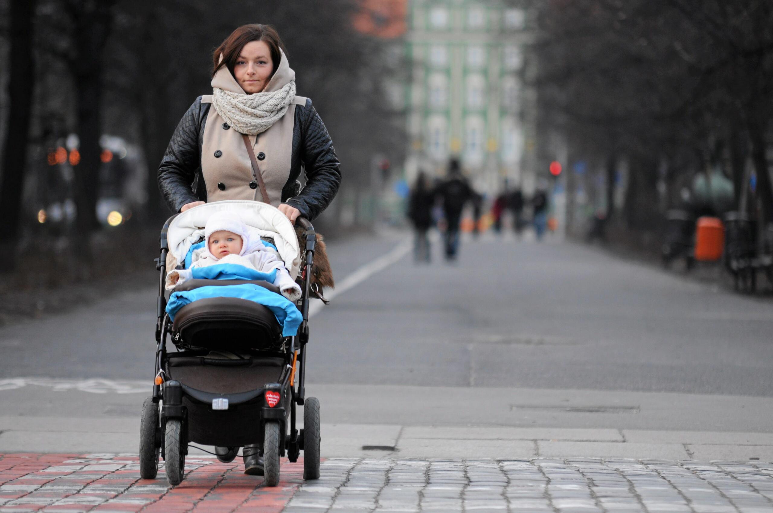 Młoda kobieta prowadzi wózek z dzieckiem