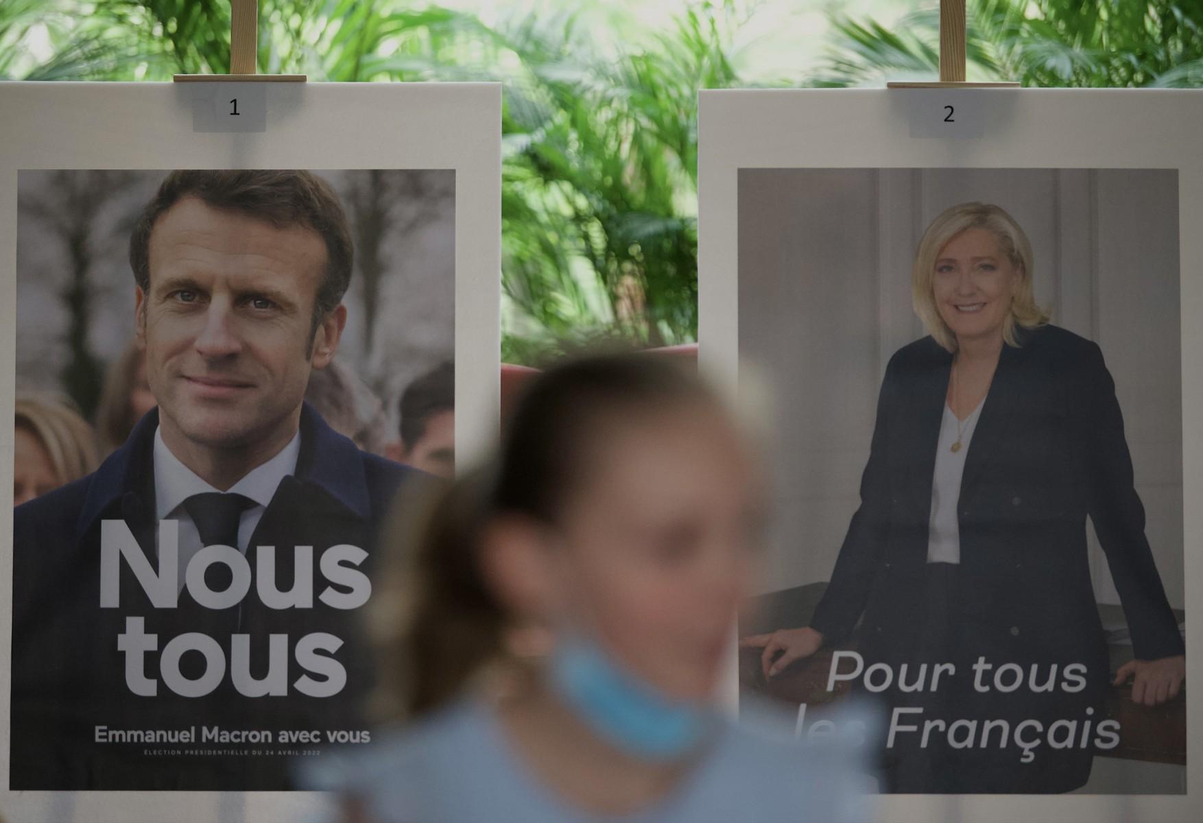 Kobieta przechodzi obok wielkich plakatów wyborczych Macrona i Le Pen