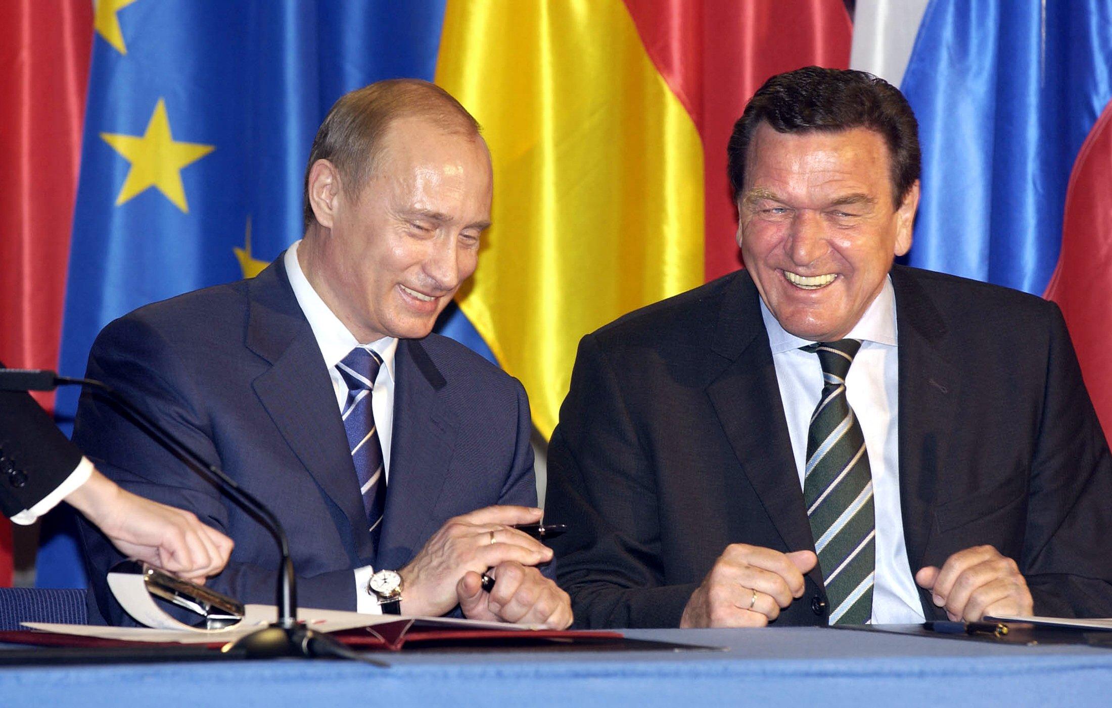 Kanclerz Niemiec Gerhard Schroeder (R) i prezydent Rosji Władimir Putin uśmiechają się podczas ceremonii podpisania umowy