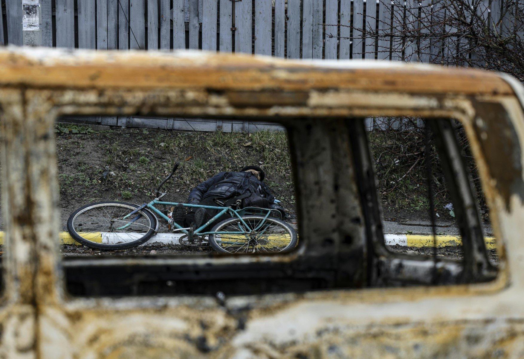 Przez okno spalonego samochody widac pobocze drogi i zabitego rowerzystę razem z jego rowerem