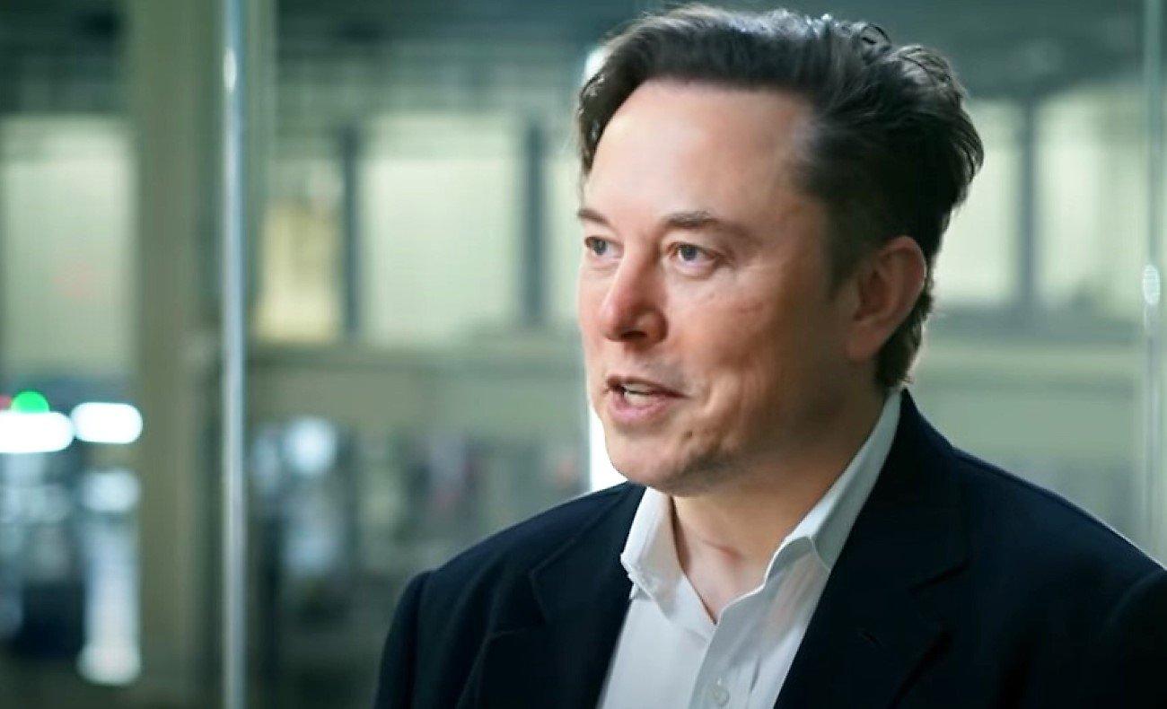 Mężczyzna w ciemnej marynarce i białej koszuli, mówi, Elon Musk