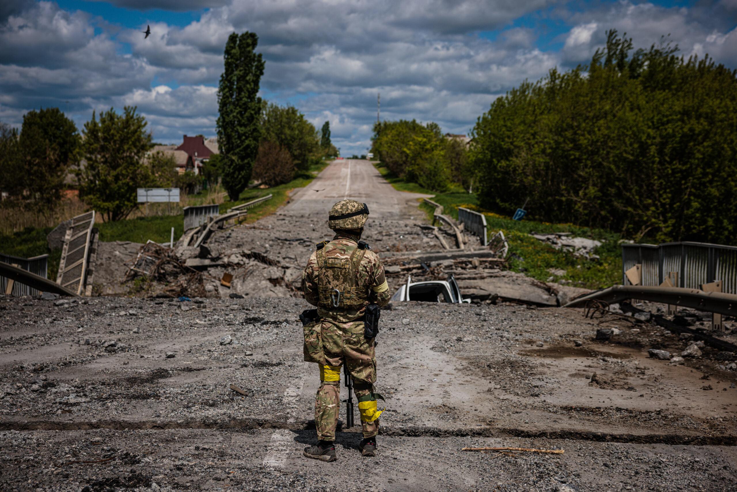 Żołnierz ukraińskiej jednostki specjalnej Kraken obserwuje teren przy zniszczonym moście na drodze w pobliżu wsi Ruśka Łozowa na północ od Charkowa, 16 maja 2022 r.