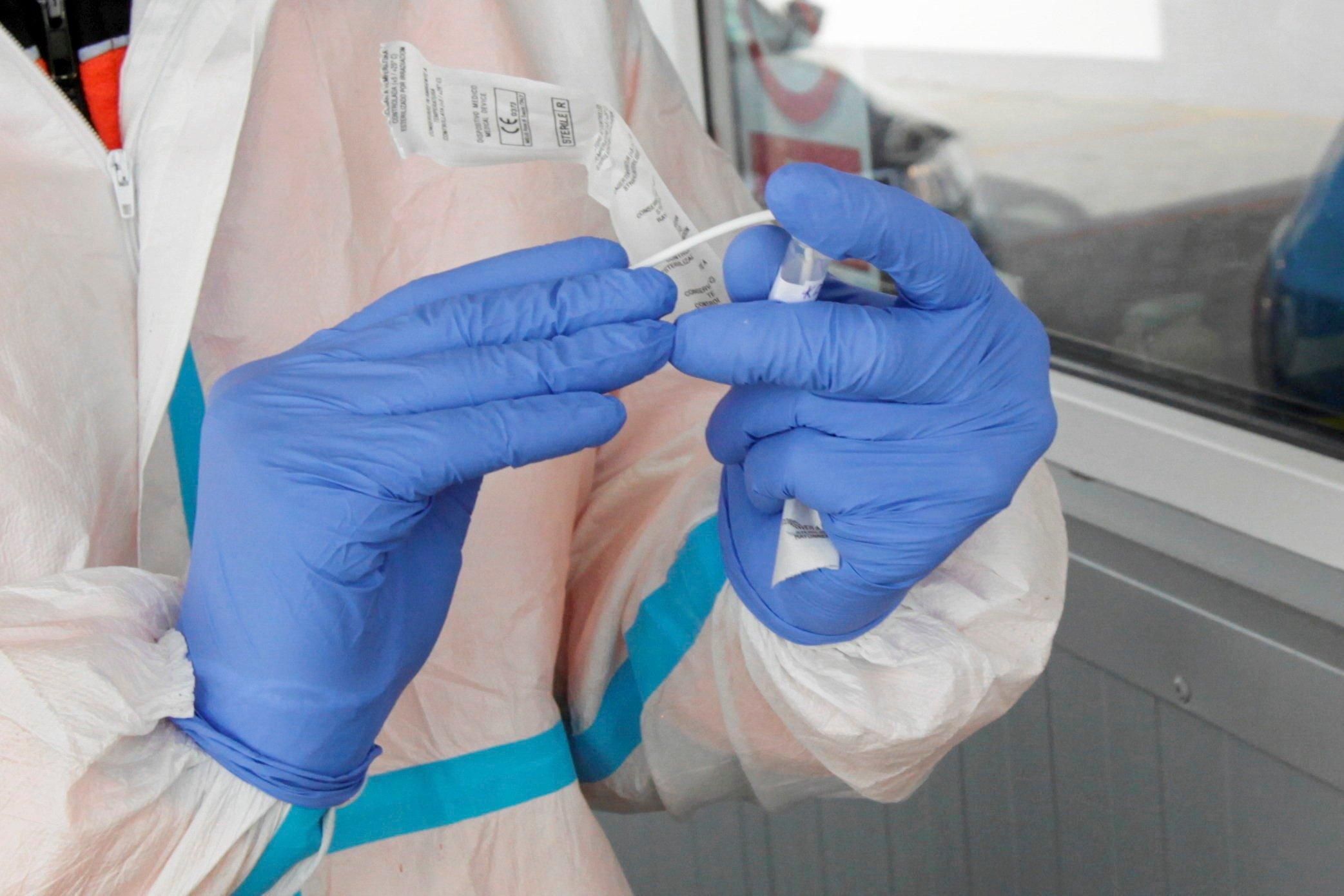 ręce w rękawiczkach ochronnych trzymają test antygenowy