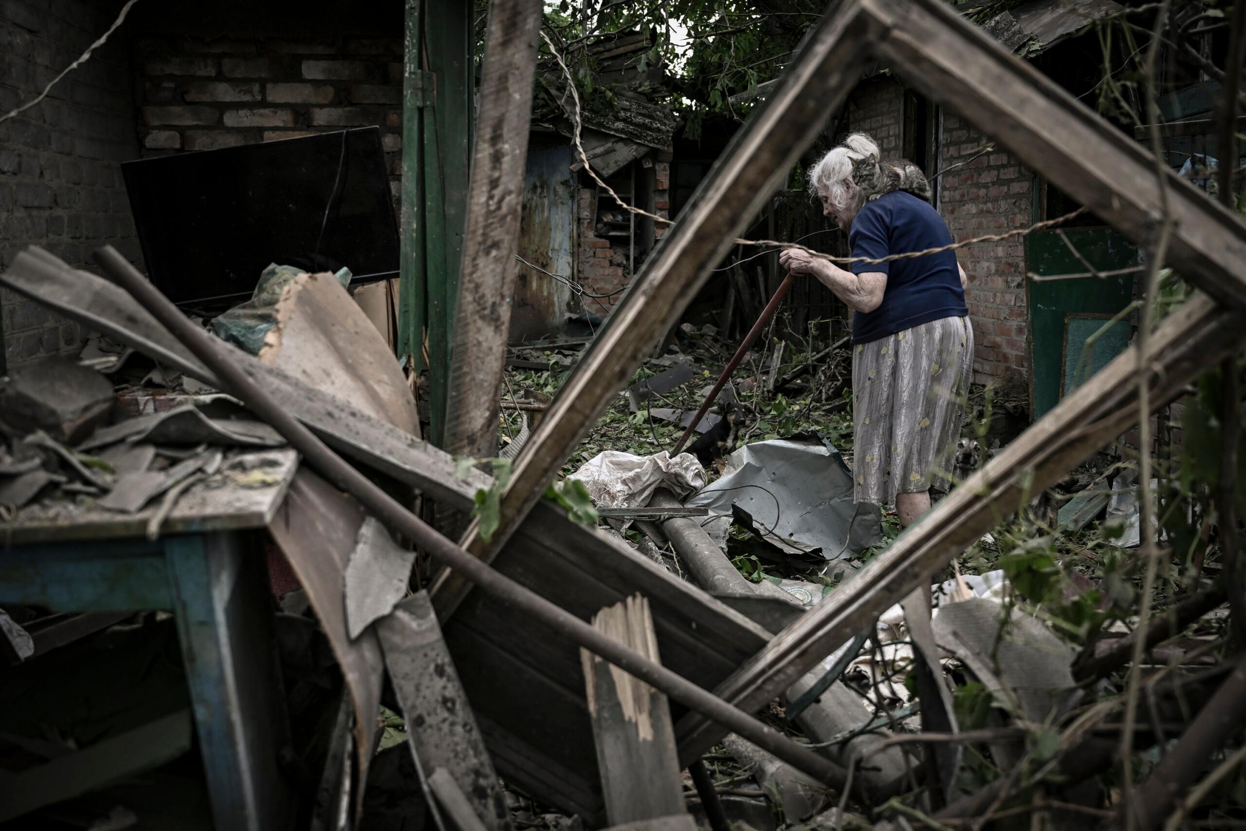 5 czerwca 2022 r. starsza kobieta z kotem na ramieniu próbuje oczyścić swoje podwórko z gruzu po uderzeniu pocisku, który zabił jedną starszą kobietę w mieście Drużkiwka na wschodzie Ukrainy, w regionie Donbas.