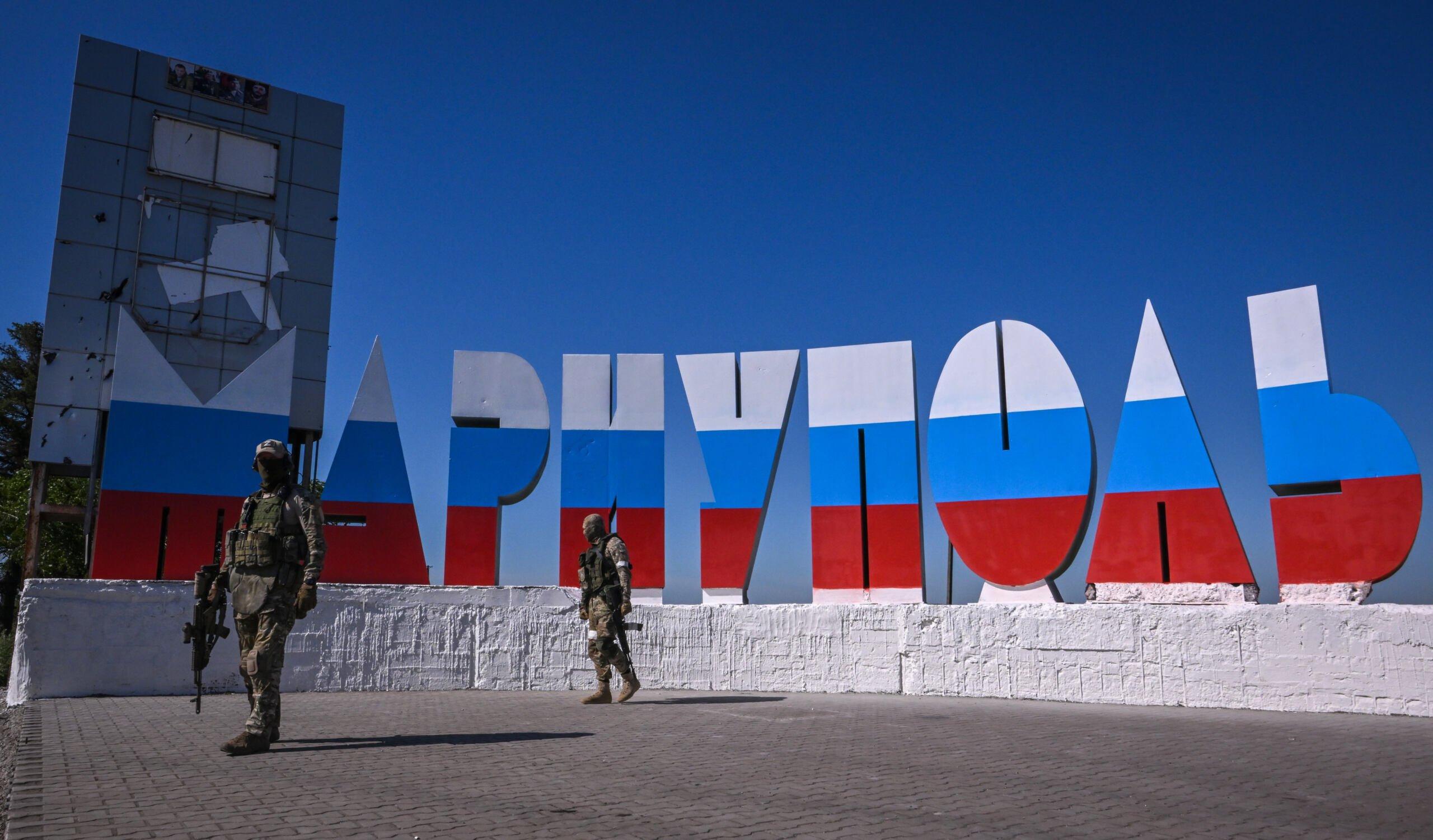 napis „Mariupol" po rosyjsku i w barwach rosyjskiej flagi, przed nim rosyjscy żołnierze