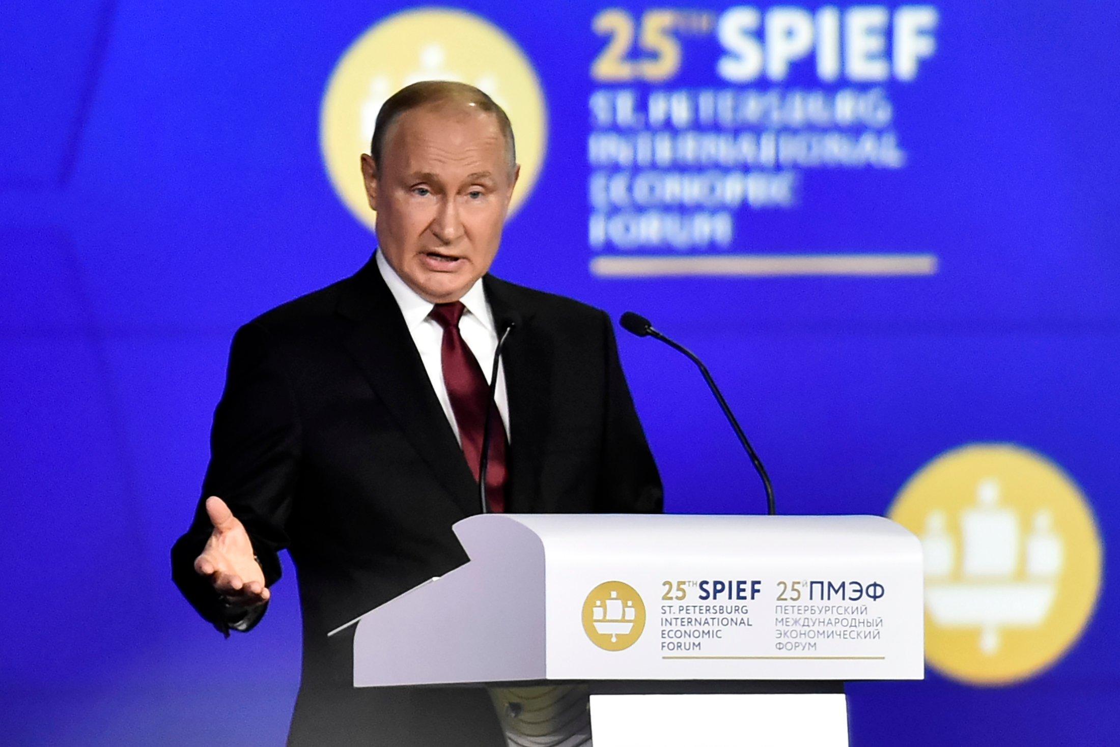 Putin przy mównicy (z aurelą z symbolu wyświetlanego w tle)