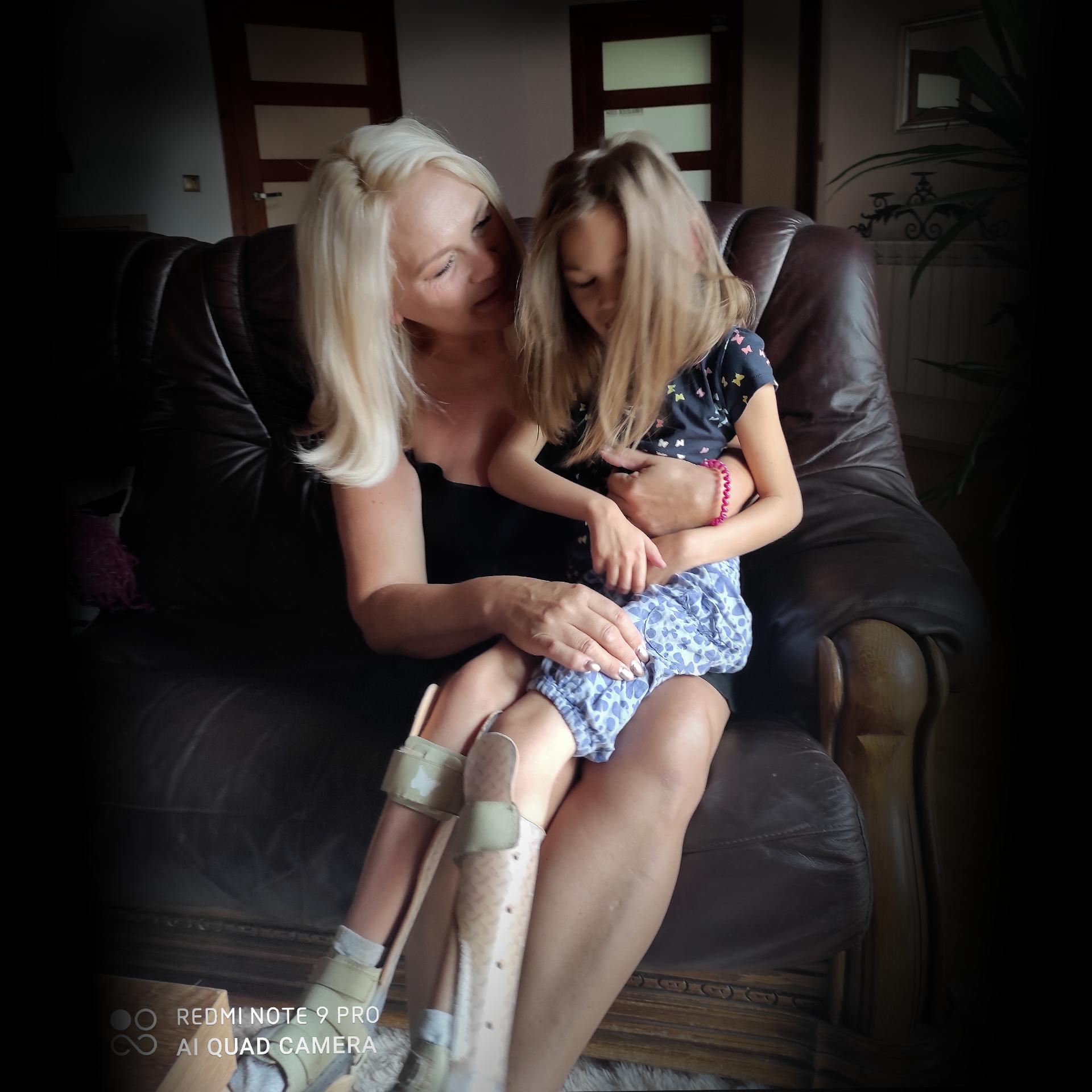 Kobieta trzymająca na kolanach niepełnosprawną córkę