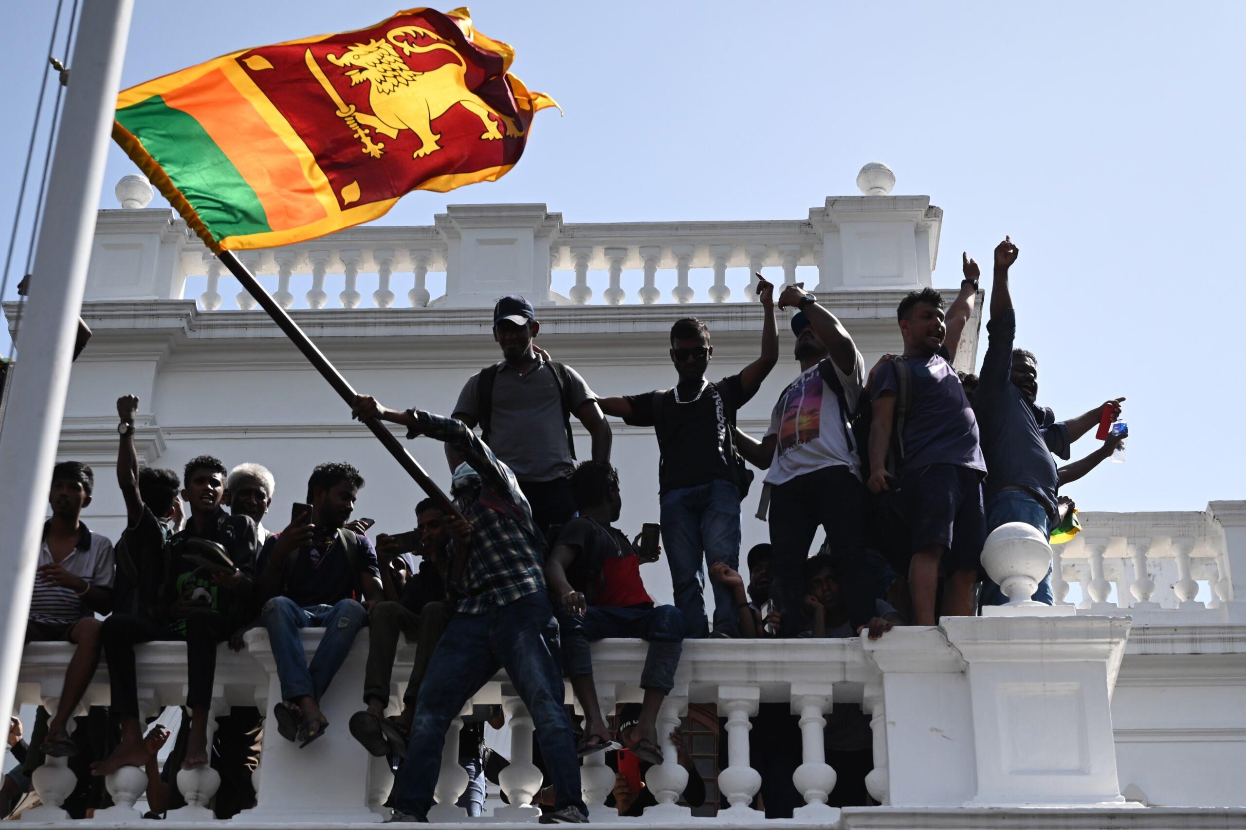 młodzi ludzie demonstrują na balkonie z flagą Sri Lanki