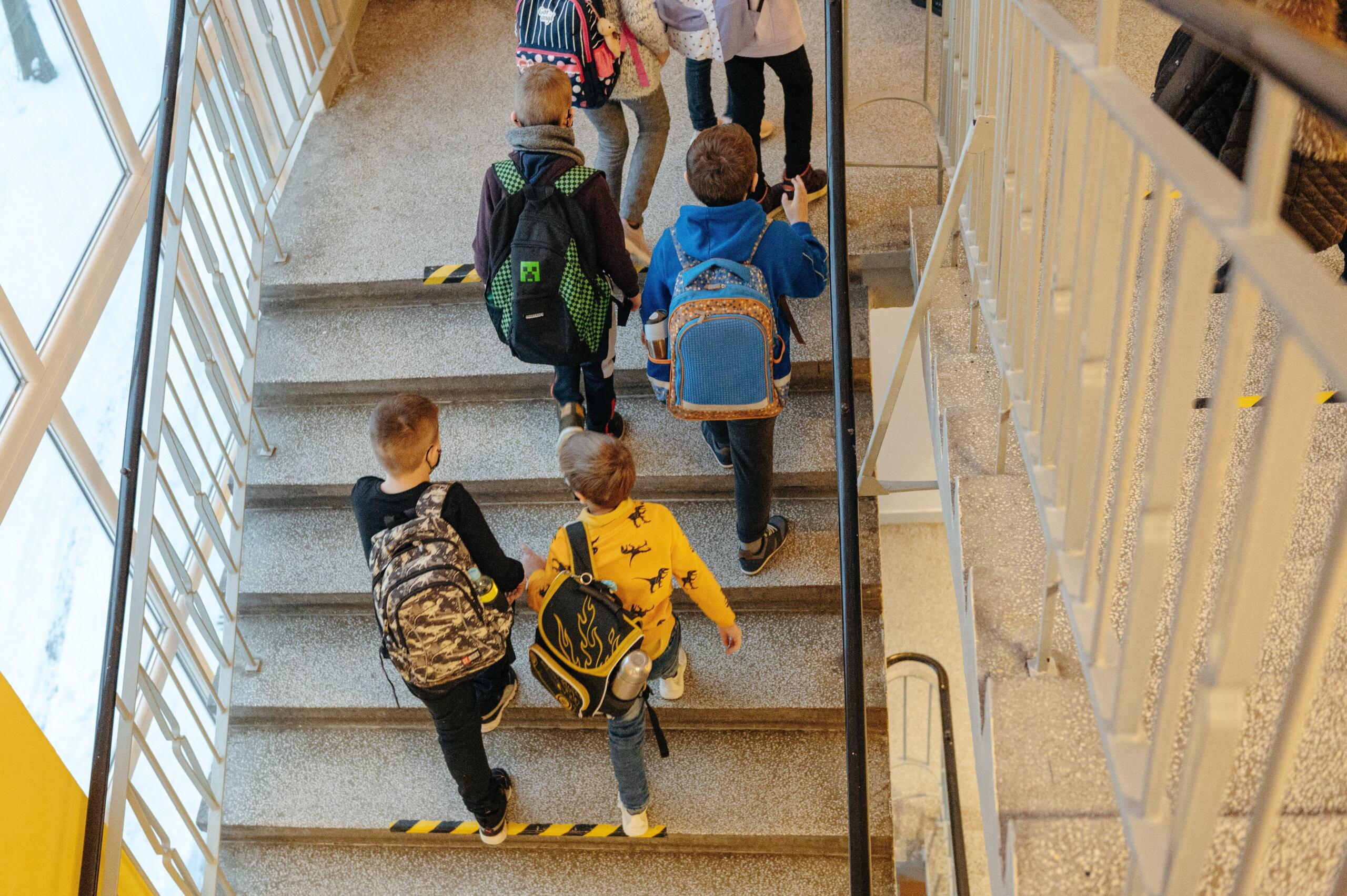 Dzieci z plecakami na schodach w szkole