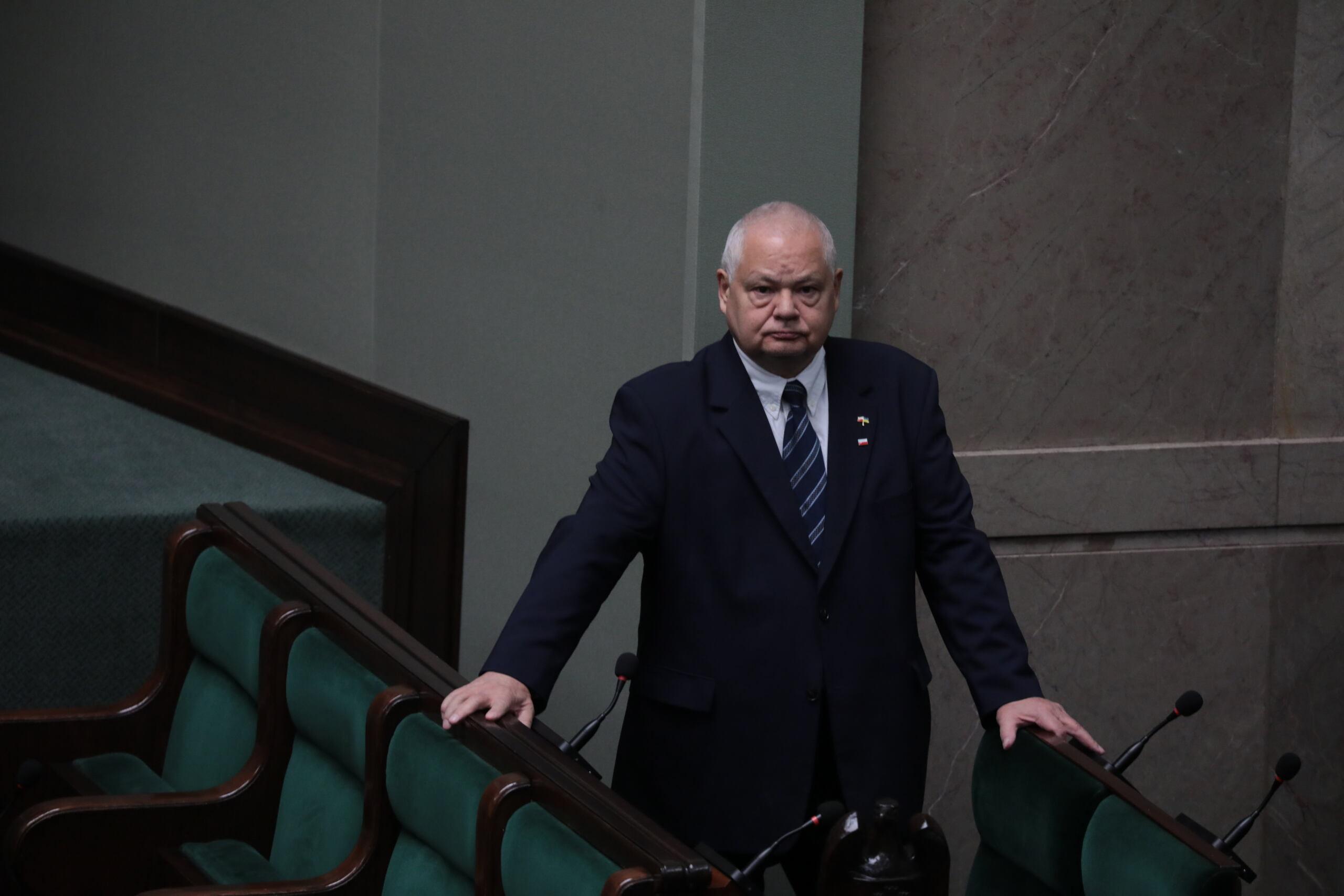 Prezes NBP Adam Glapiński czeka w Sejmie na swoje przemówienie z naburmuszoną miną.