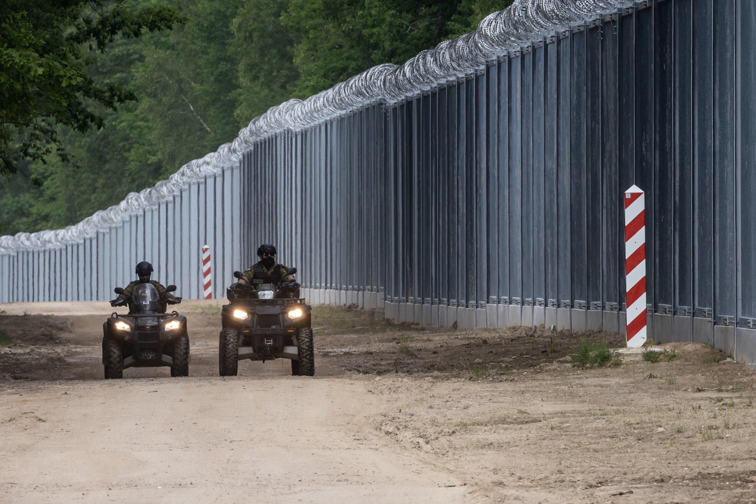 Mur na polsko-białoruskiej granicy, funkcjonariusze Straży Granicznej jadą wzdłuż niego na quadach