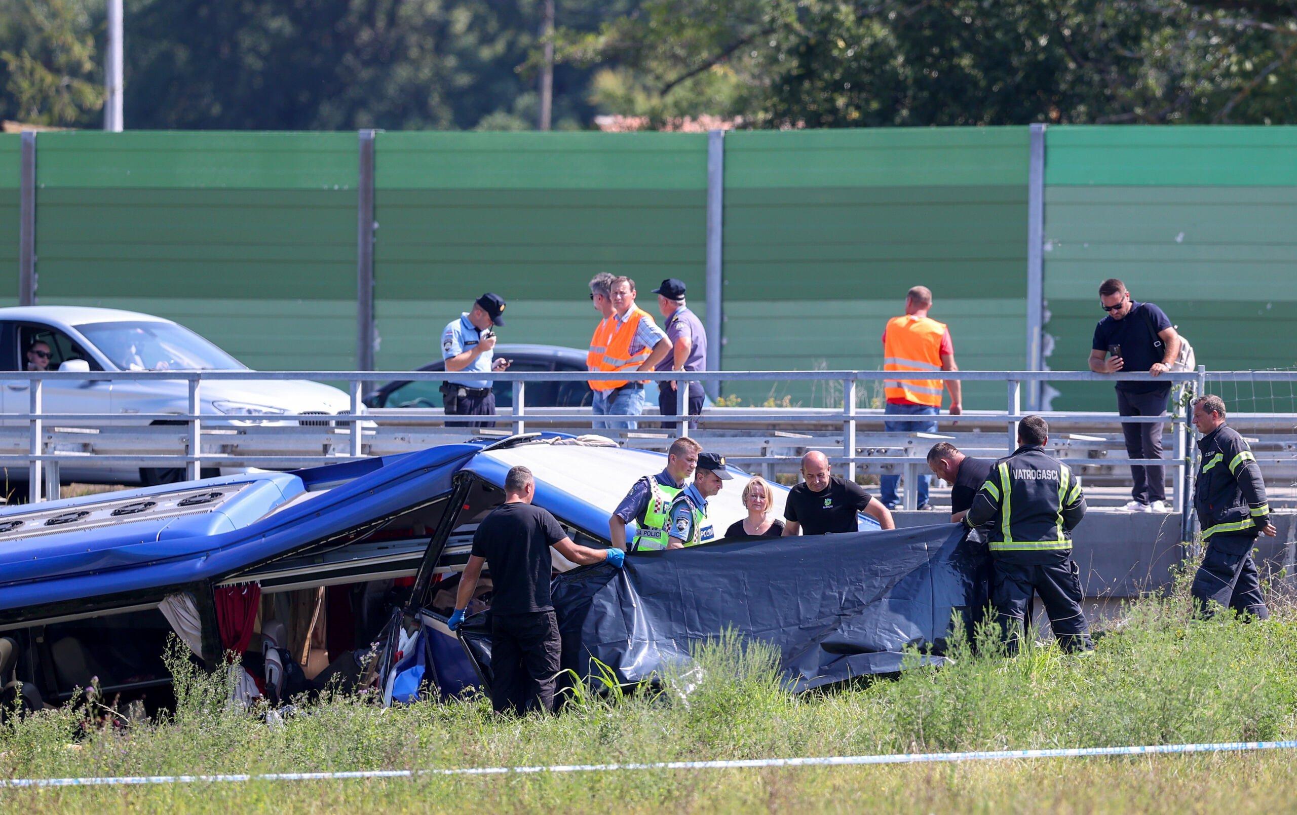 Członkowie policji i służb ratowniczych pracują na autostradzie Varaždin-Zagrzeb obok wraku autobusu po wypadku, który wydarzył się wczesnym rankiem około 50 kilometrów od Zagrzebia, 6 sierpnia 2022 roku.