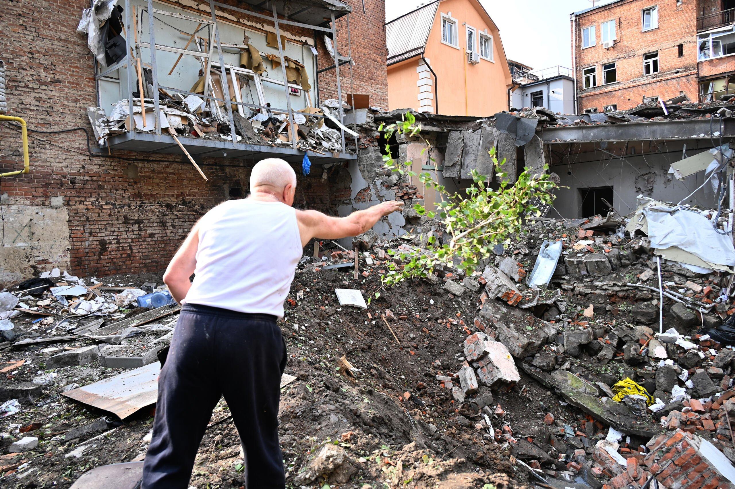 Mężczyzna wskazuje ręką na ruiny domu po trafieniu rosyjską rakietą
