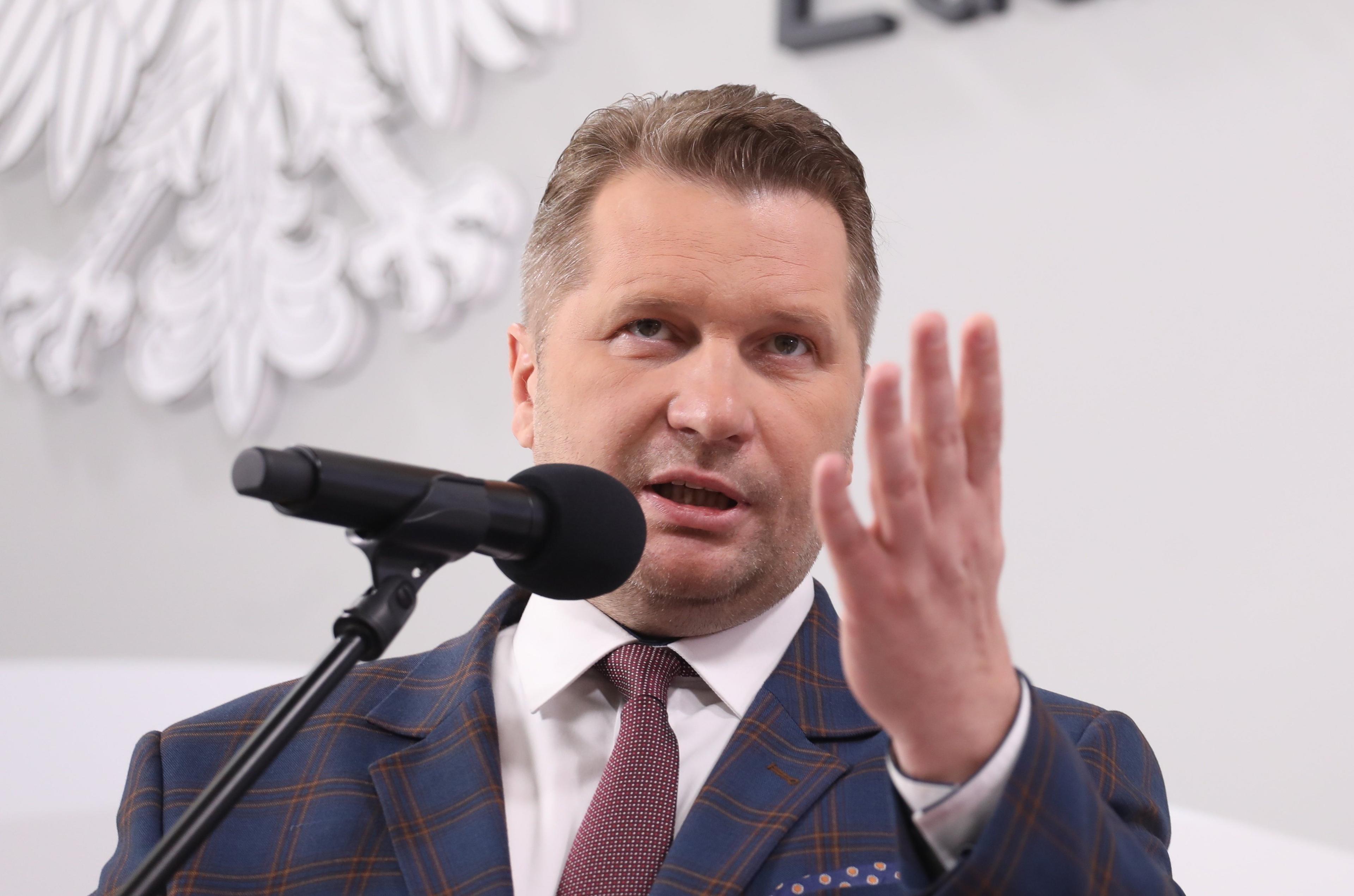Minister Czarnek gestykuluje przed mikrofonem