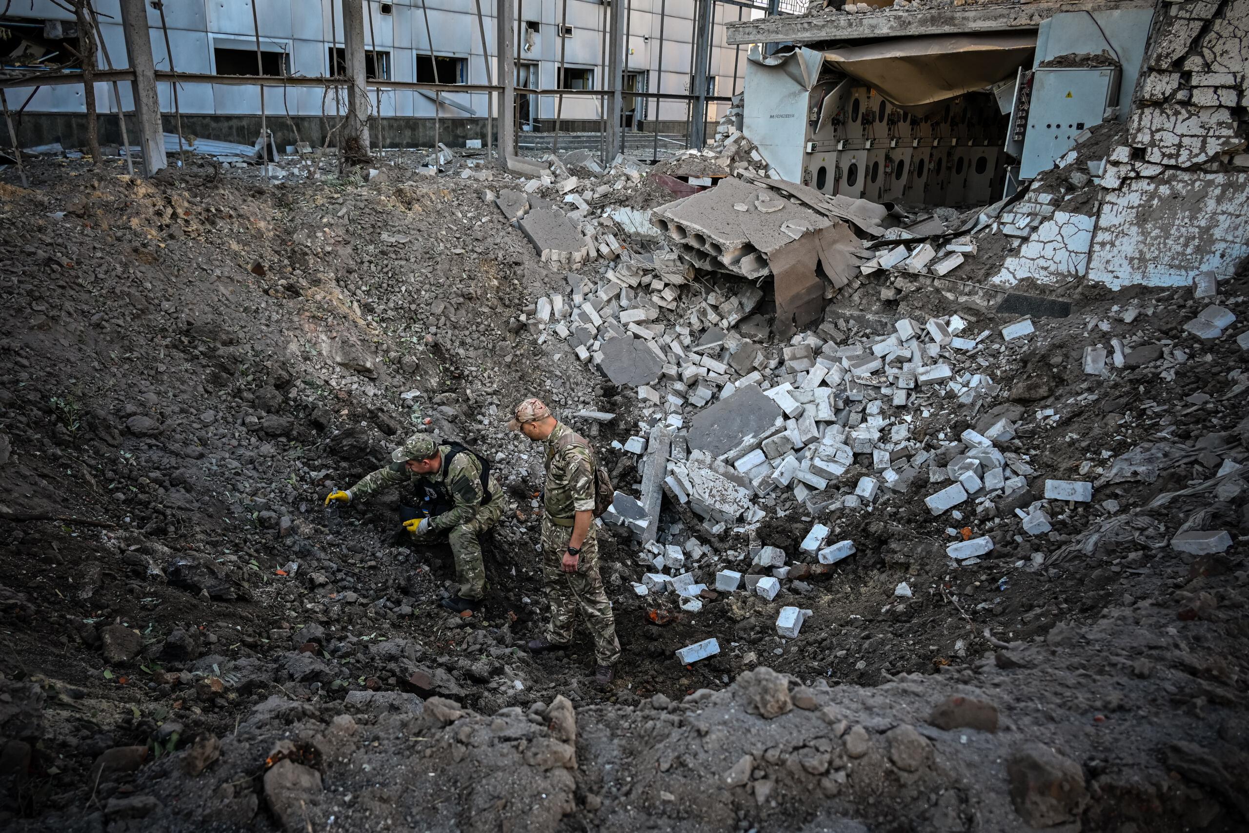 Ukrainian servicemen examine a crater following a missile strike in centre of Kharkiv on September 2, 2022, amid the Russian invasion of Ukraine. (Photo by SERGEY BOBOK / AFP)