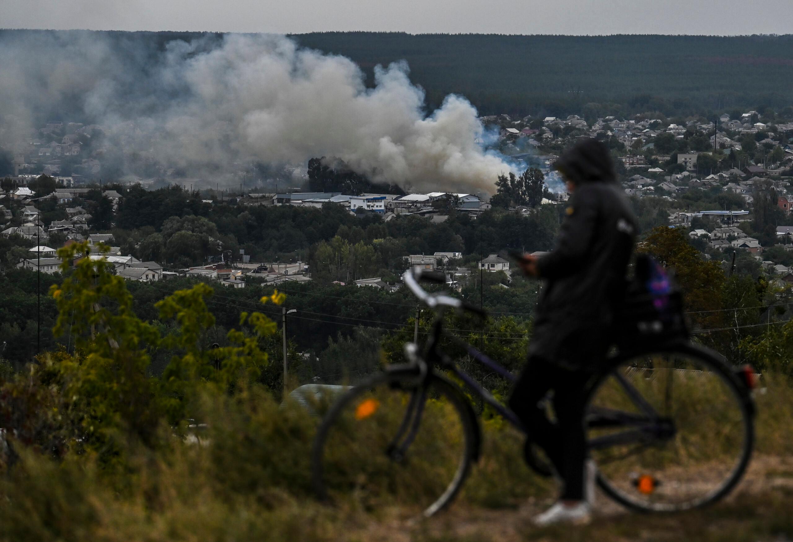 This photograph taken on September 11, 2022, shows a cyclist looking at a smartphone on a hill overlooking Izyum, Kharkiv Region, eastern Ukraine, amid the Russian invasion of Ukraine. - Ukraine forces said that their lightning counter-offensive took back more ground in the past 24 hours, as Russia replied with strikes on some of the recaptured ground. The territorial shifts were one of Russia's biggest reversals since its forces were turned back from Kyiv in the earliest days of the nearly seven months of fighting, yet Moscow signalled it was no closer to agreeing a negotiated peace. (Photo by Juan BARRETO / AFP)