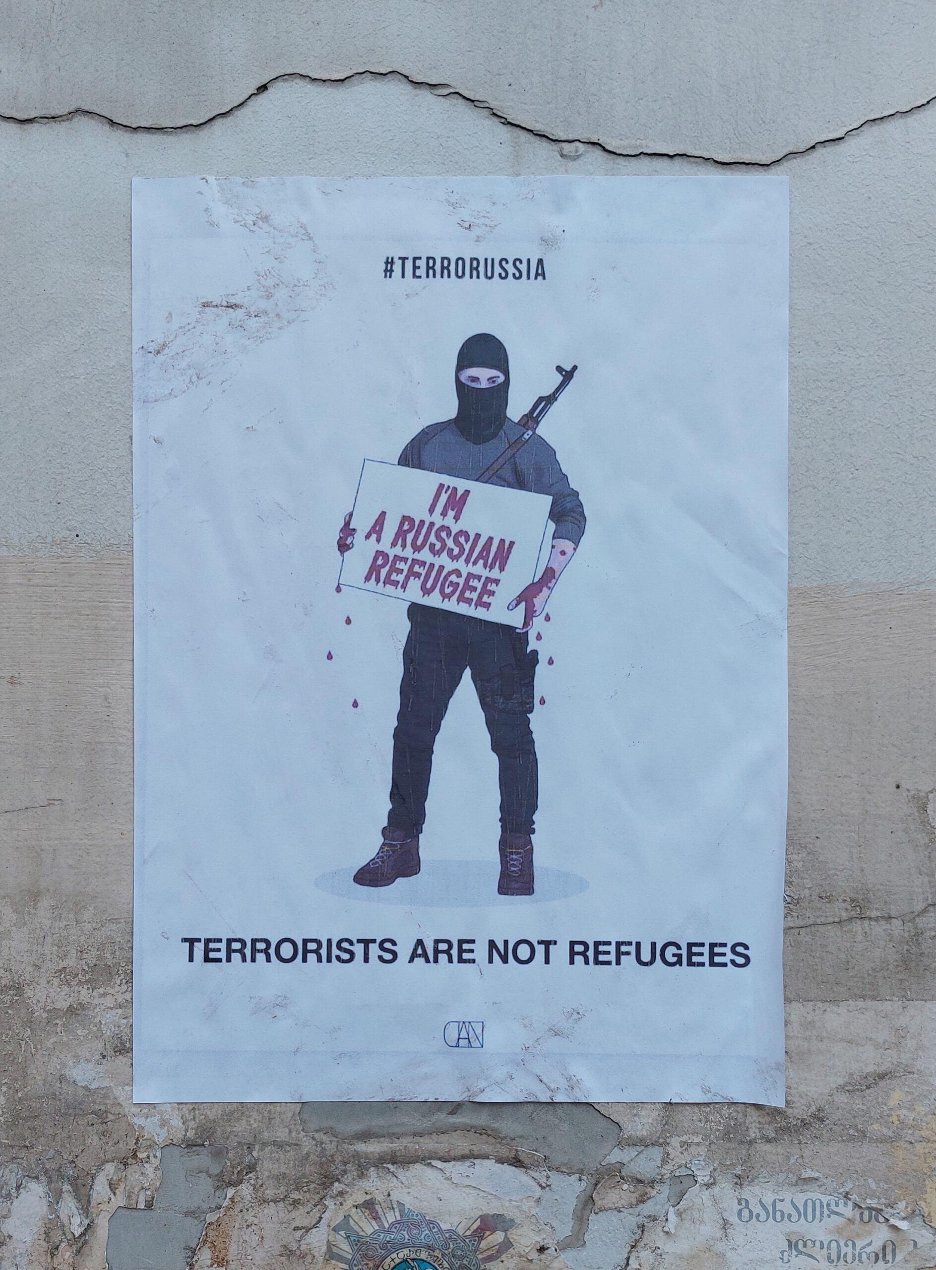 plakat na murze, z napisem po angielsku "Terroryści nie są uchodźcami"