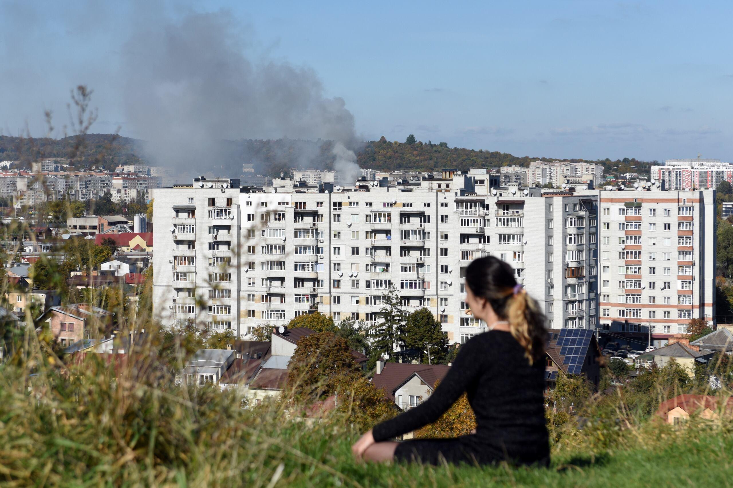 Kobieta patrzy ze wzgórza na dym nad miastem