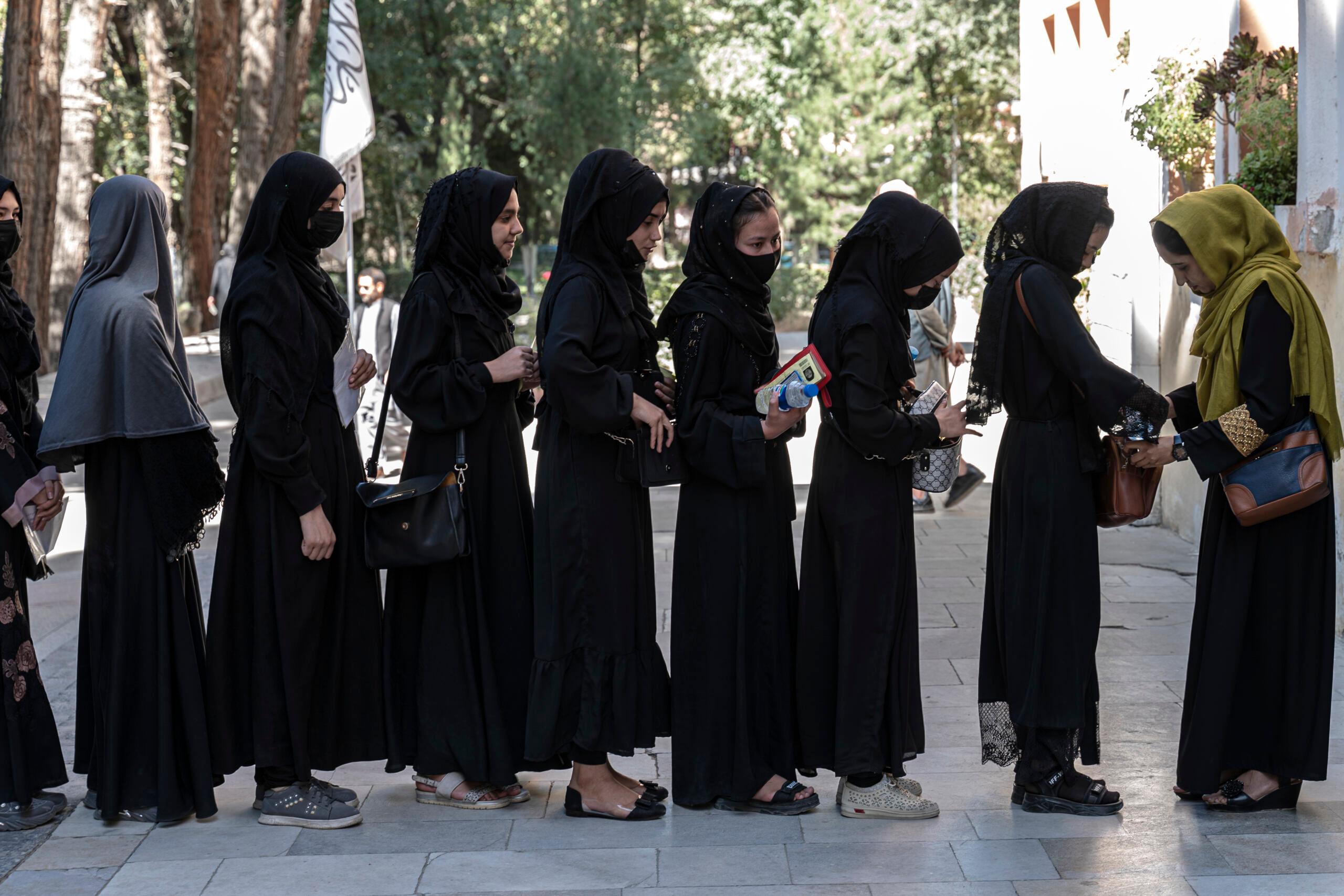 Kobiety w szczelnie zakrtwających czarnych strojach stoją w kolejce