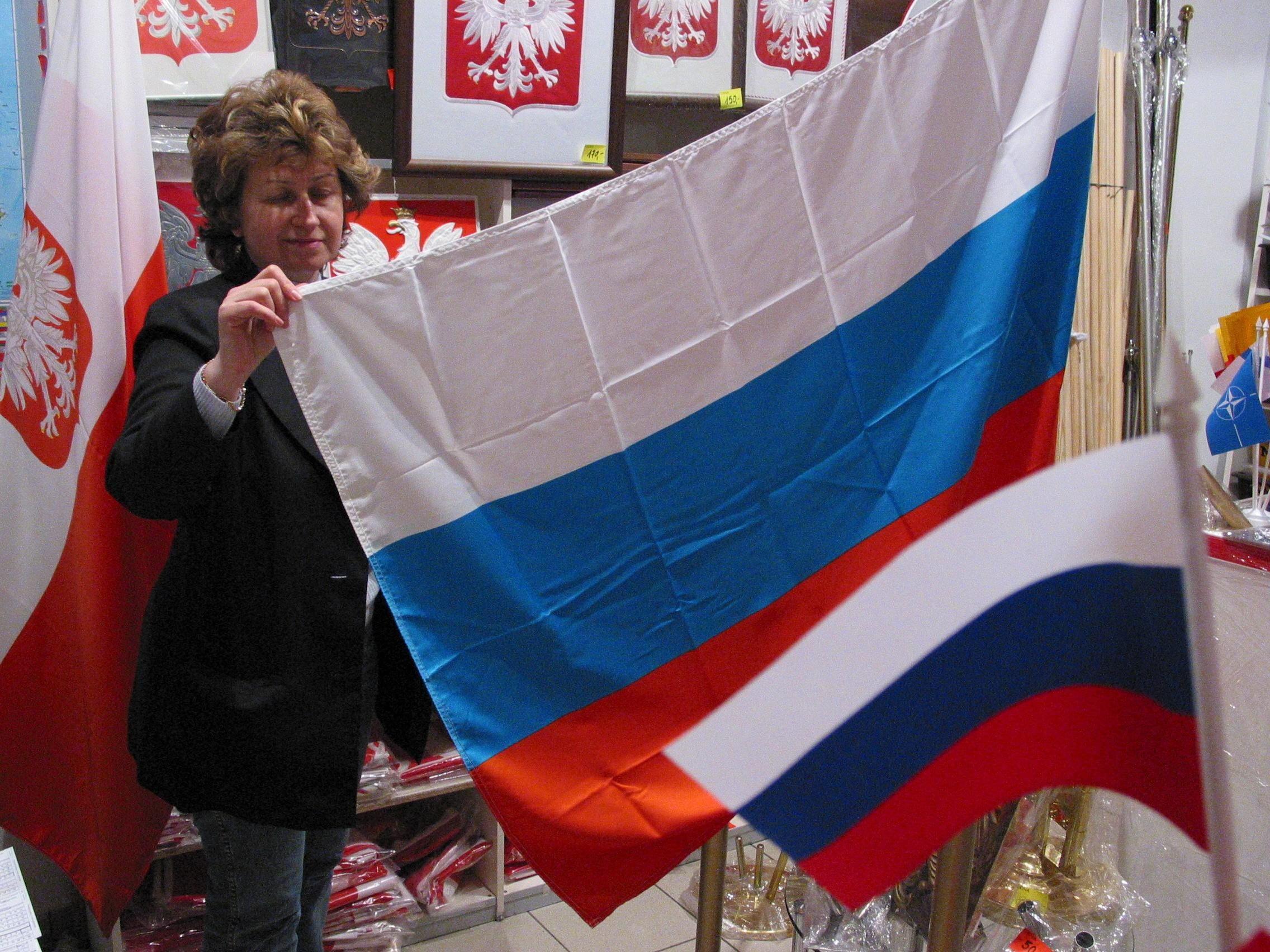 Kobieta pokazuje rosyjską flagę, na ścianie wiszą polskie orły herbowe
