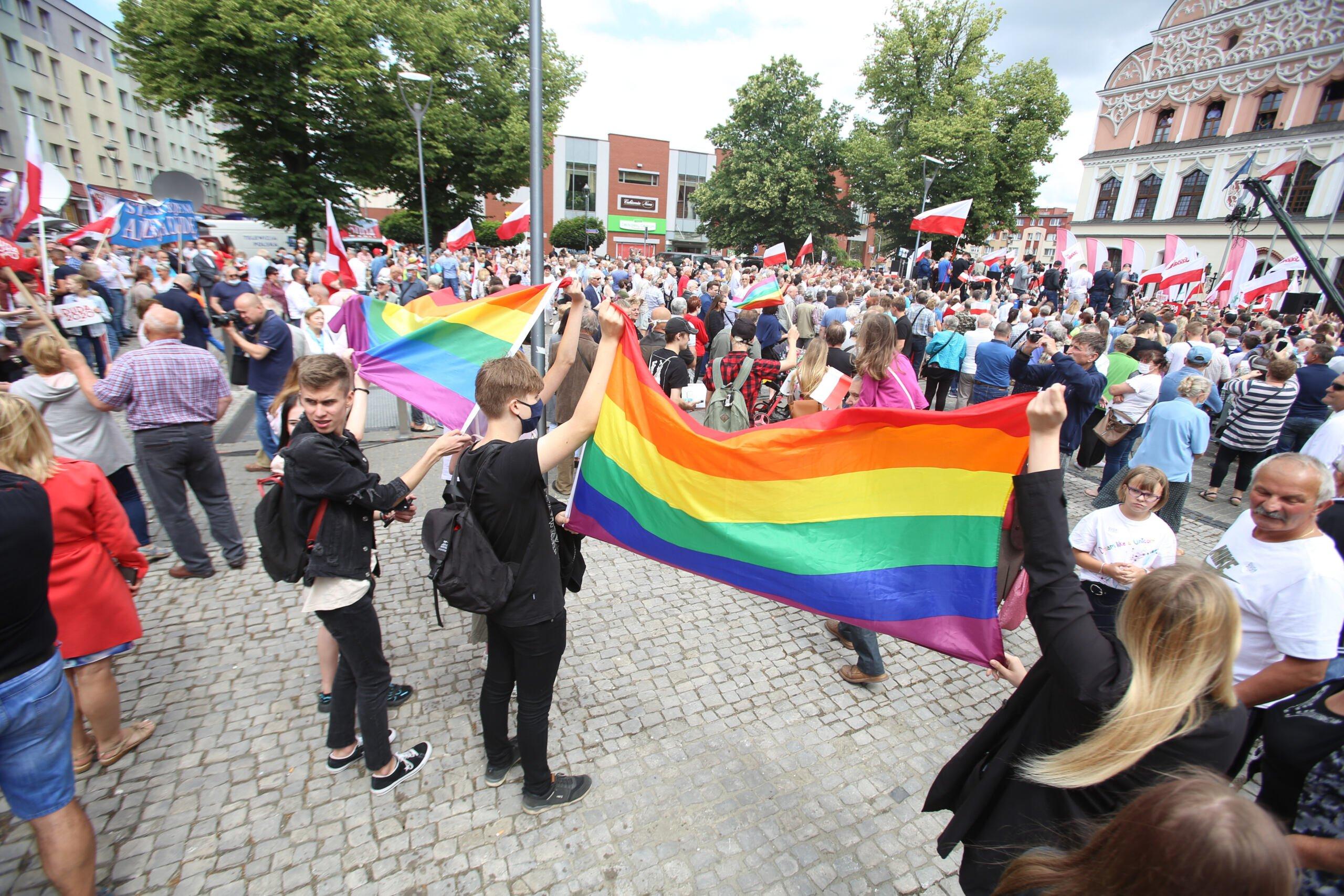 ludzie manifestują na ulicy z flagami Polski i flagami tęczowymi
