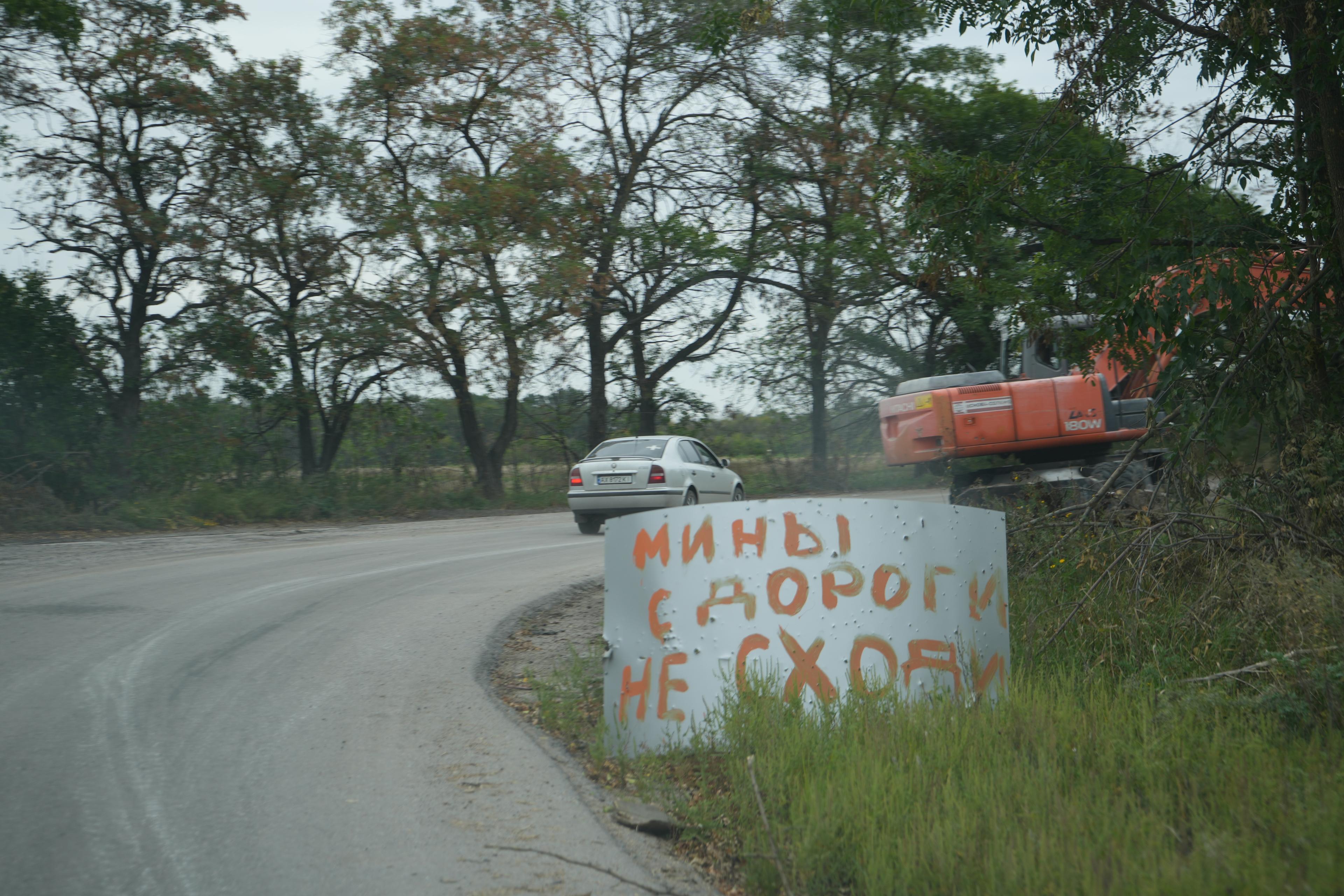 Rosyjski napis na zakręcie drogi w polu