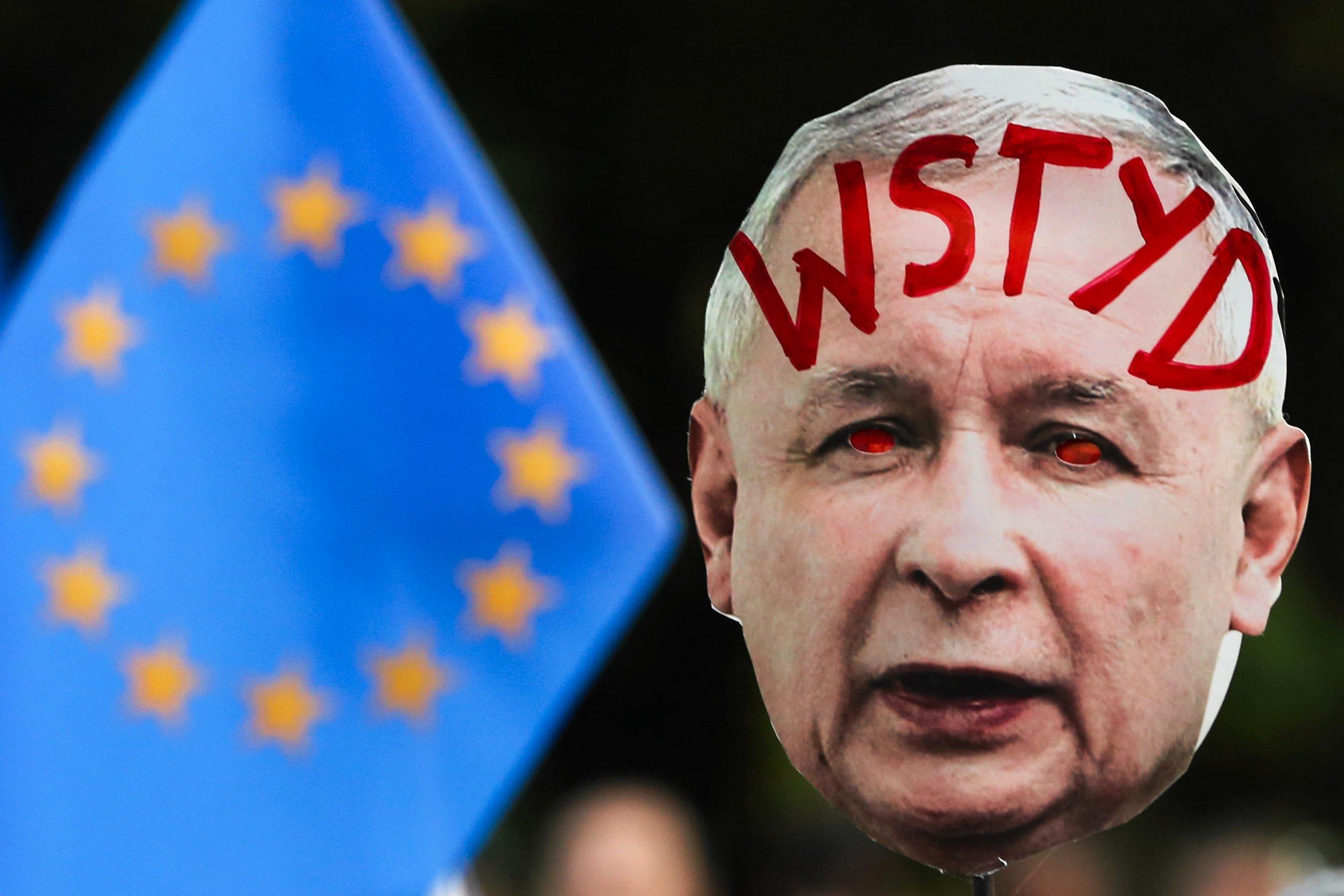 maska z podobizną Jarosława Kaczyńskiego i napisem na czole "wstyd", na tle flagi Unii Europejskiej
