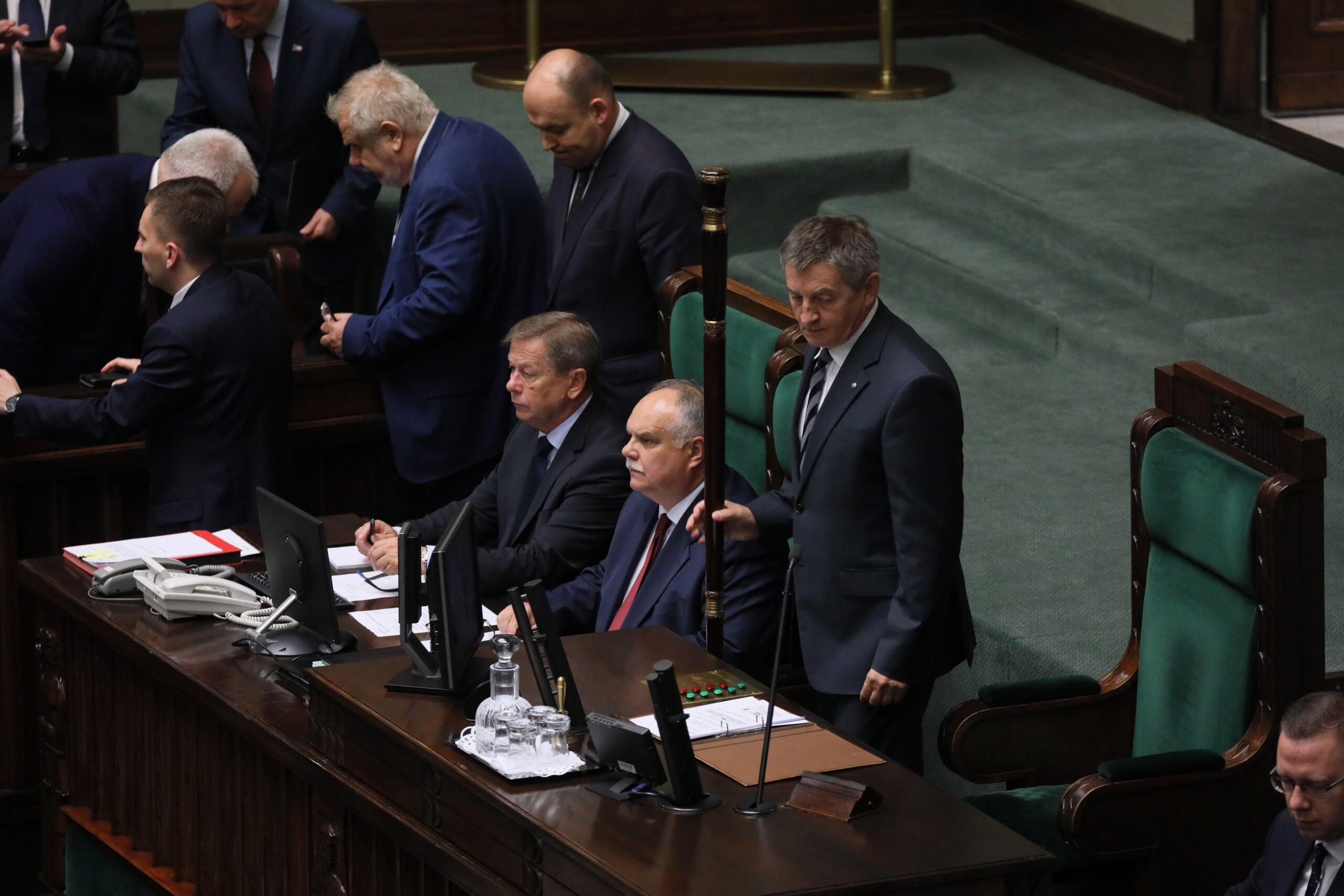 Poseł PiS Marek Kuchciński stoi w miejscu przeznaczonym dla marszałka Sejmu, obok niego laska marszałkowska