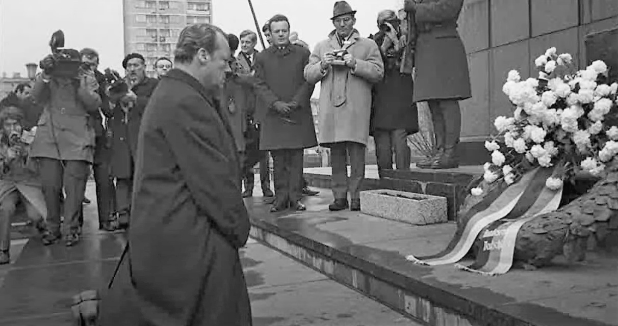 Niemiecki kanclerz Willy Brandt klęczy przed Pomnikiem Bohaterów Getta, pochmurny grufnioey dzień, Brandt w płaszczu
