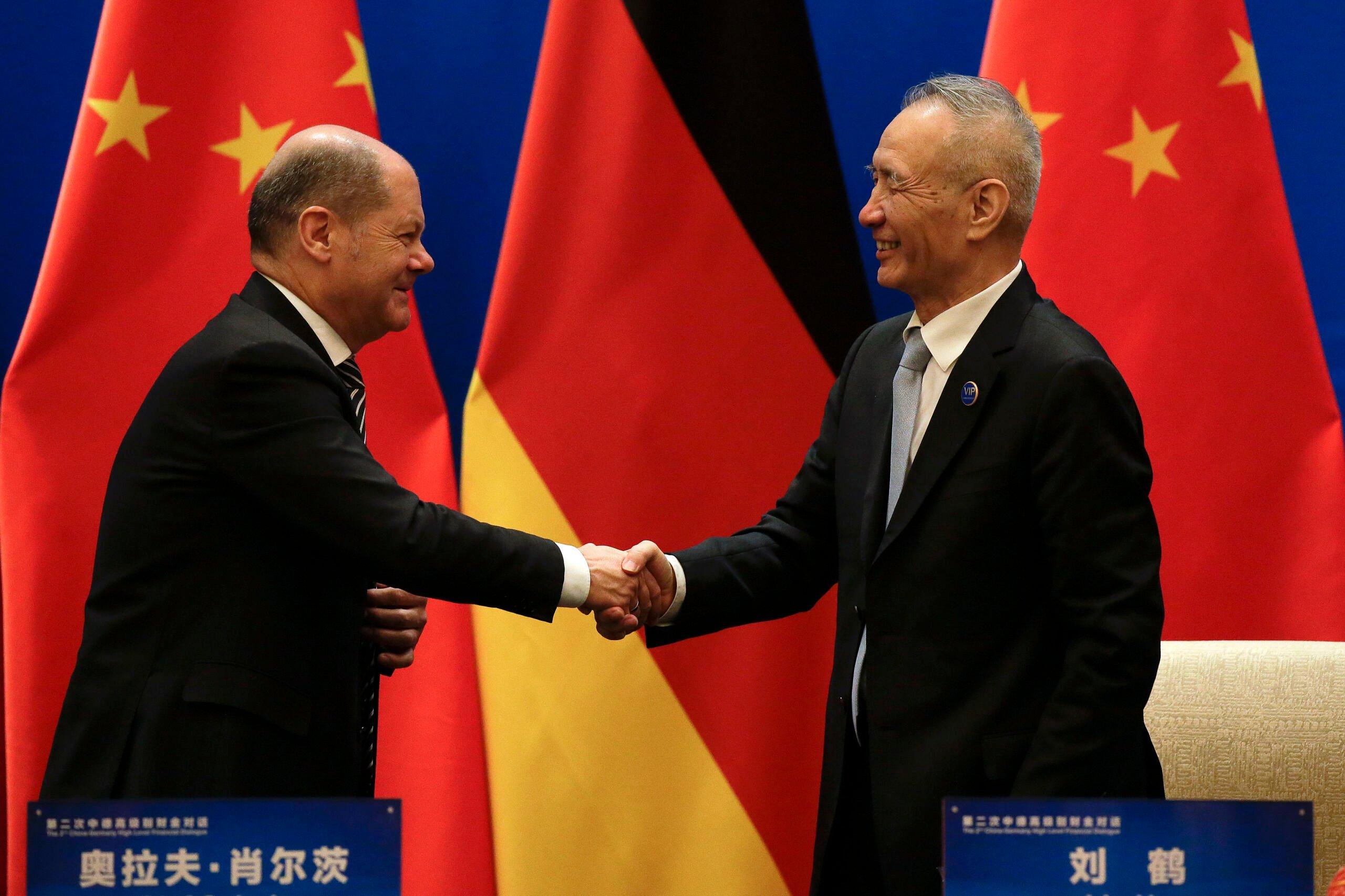 Europejczyk i Chińczyk ściskający sobie ręce na tle flag Chin i Niemiec