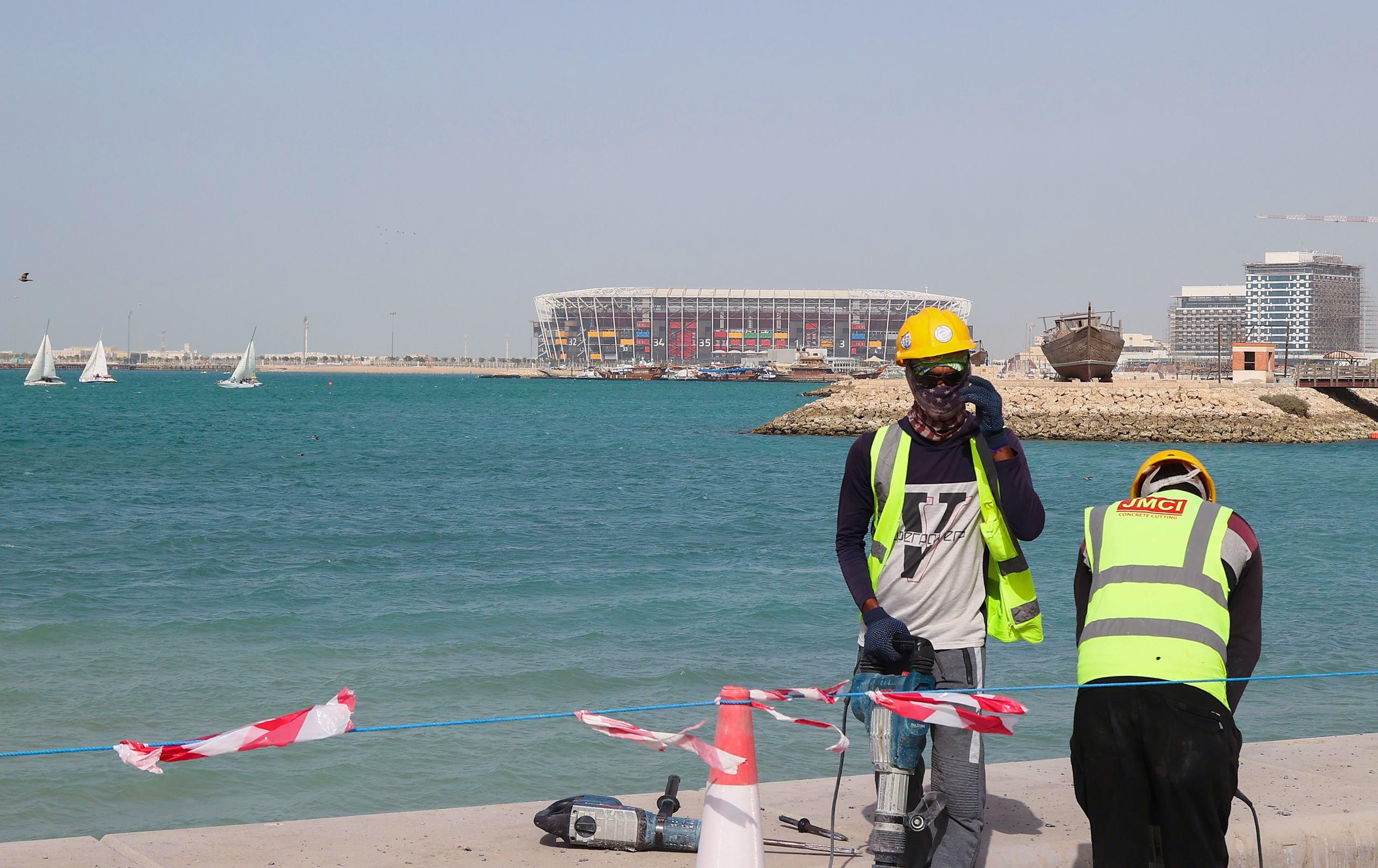 A picture taken on May 21, 2022, shows workers across from the 974 Stadium, formerly knows as Ras Abu Aboud, in the Qatari capital Doha, which will host matches of the FIFA football World Cup 2022. (Photo by KARIM JAAFAR / AFP)