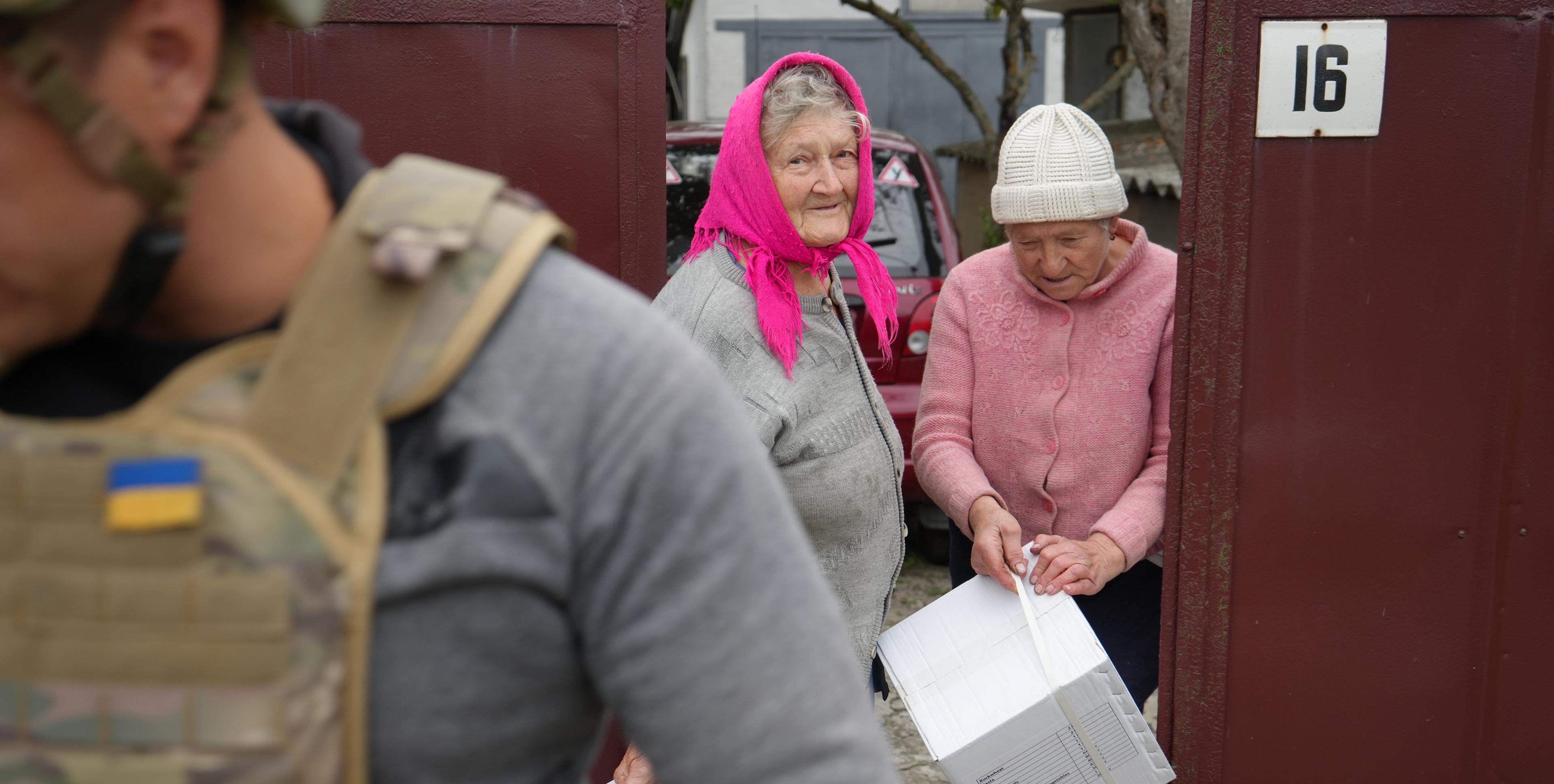 dwie starsze kobiety trzymają paczki z pomocą humanitarną.