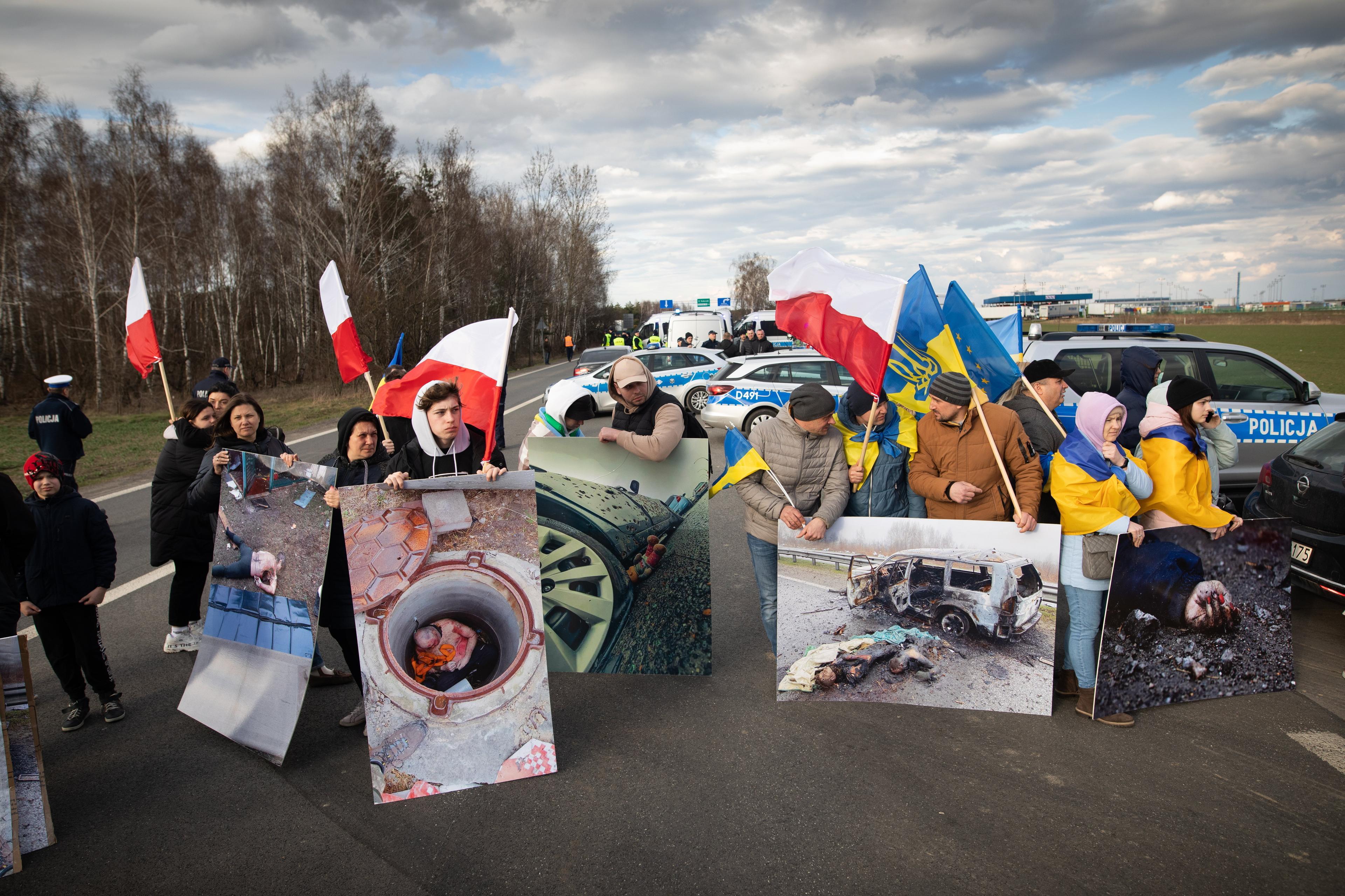 Protest: ludzie stoja w poprzek drogi z polskimi i ukraińskimi flagami, nie pozwalając przejeżdżać ciężarówkom
