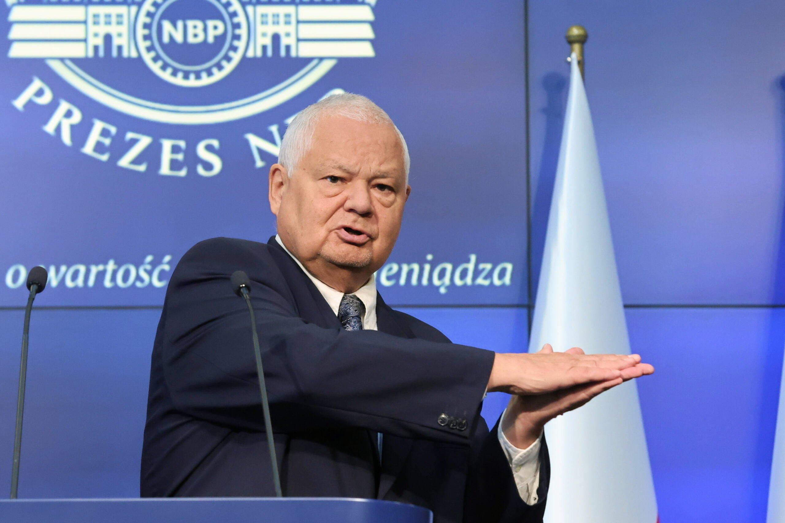 Prezes NBP Adam Glapiński podczas konferencji prasowej w siedzibie NBP na tle niebieskiego ekranu