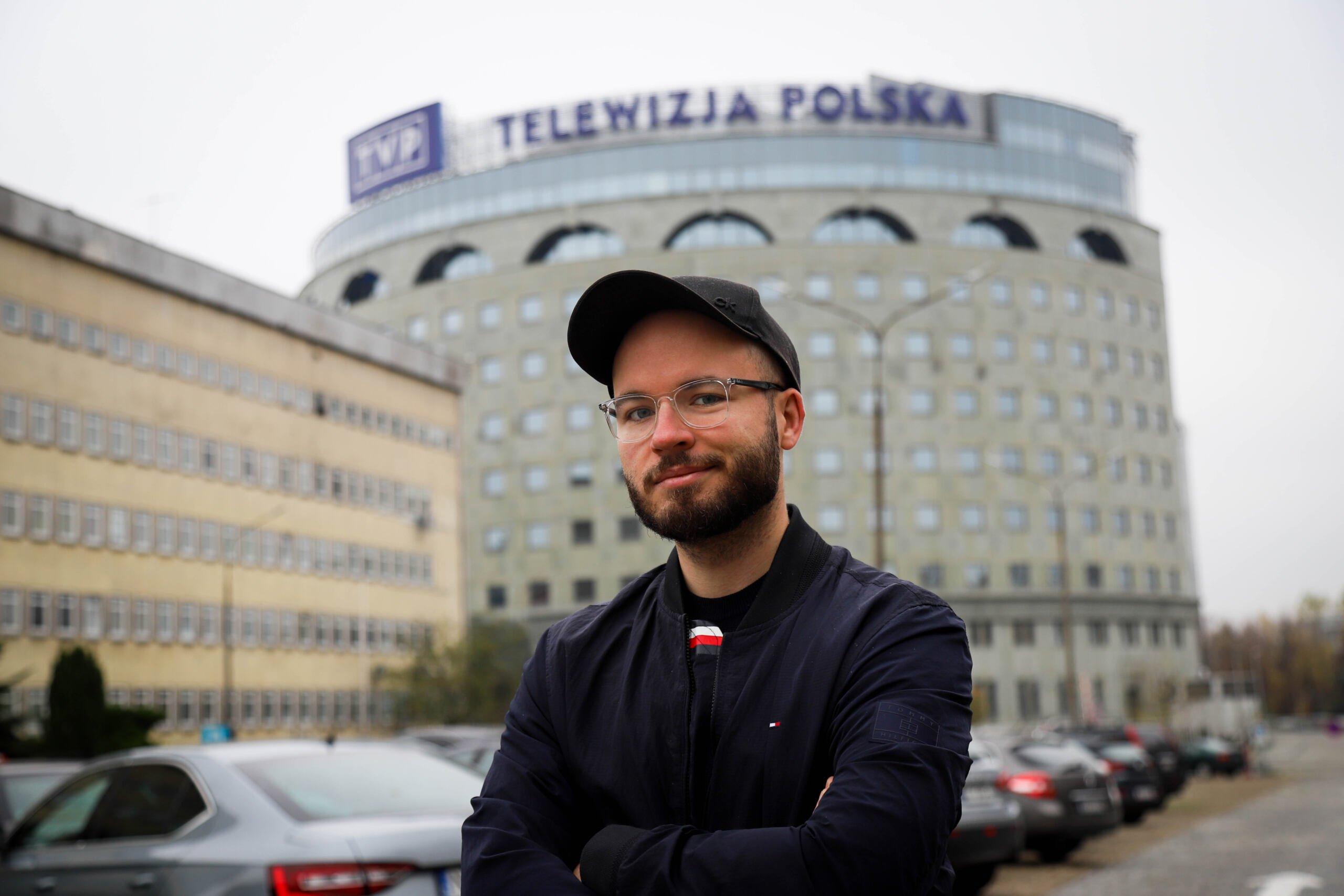 Mężczyzna w czapce z daszkiem (Bart Staszewski) przed budynkiem TVP