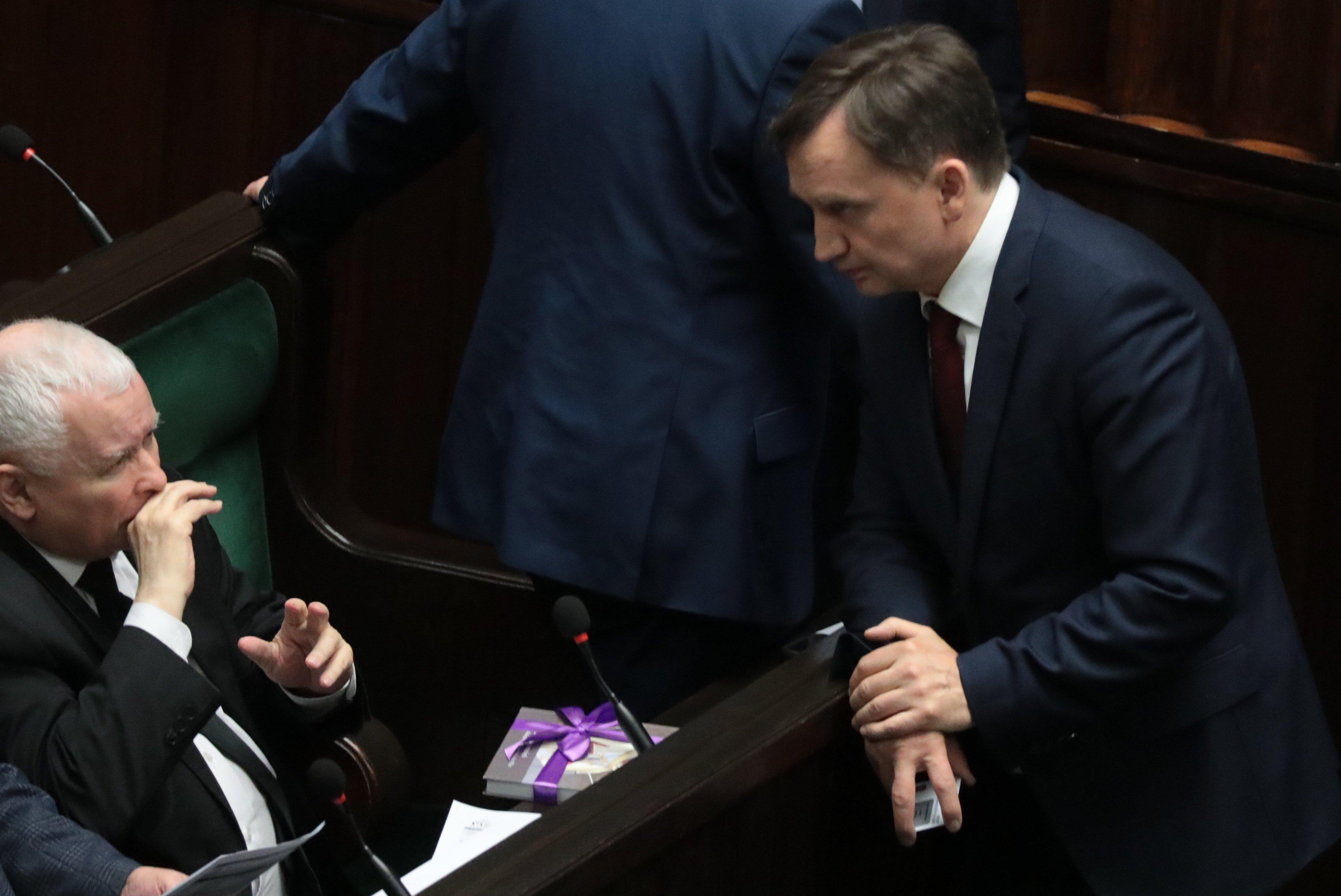 Jarosław Kaczyński siedzi w ławie poslelskiej, pochyla sie nad nim Zbigniew ZIobro