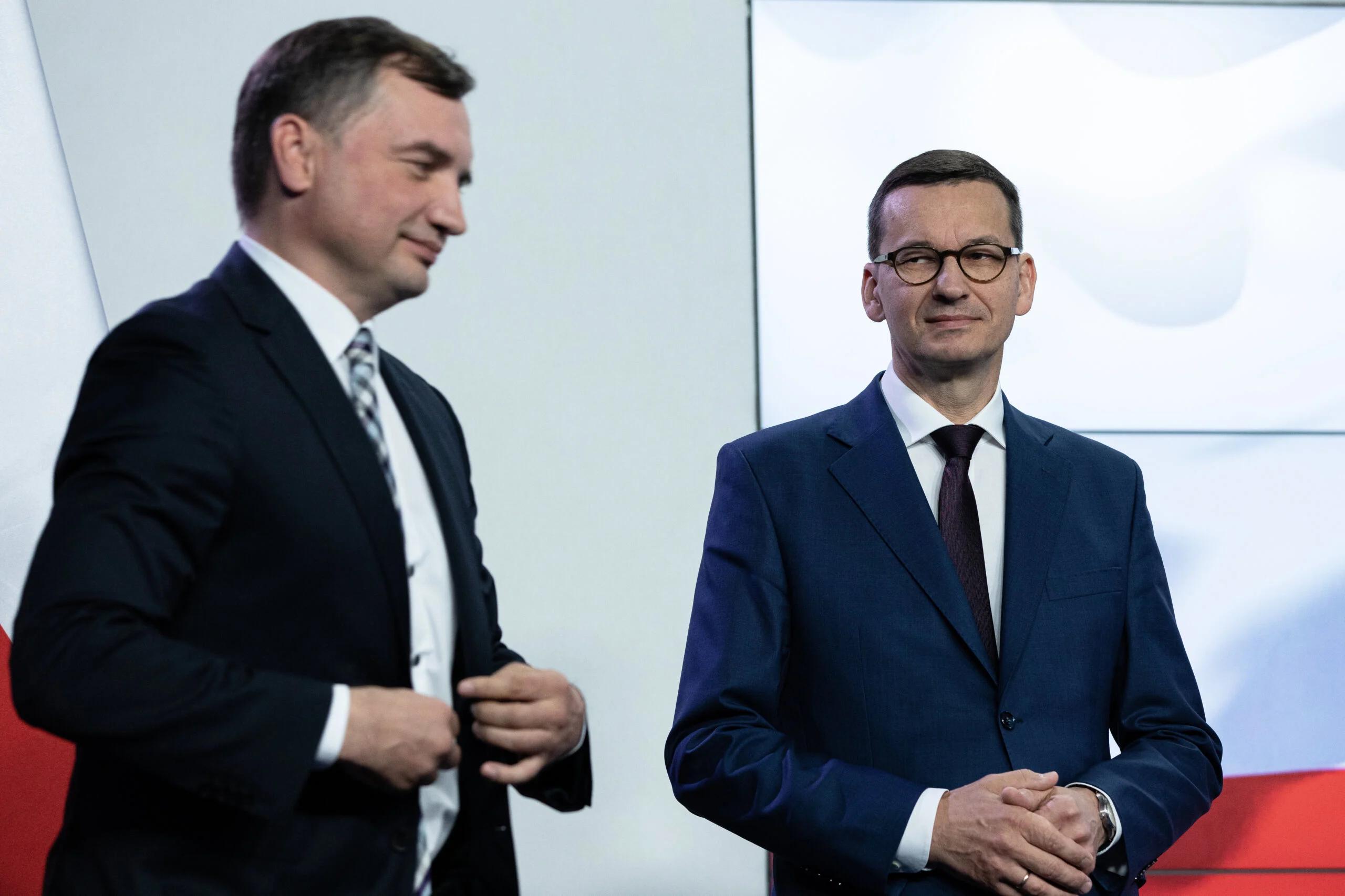 Minister Zbigniew Ziobro stoi na konferencji prasowej obo premiera Mateusza Morawieckiego, obaj panowie się uśmiechają