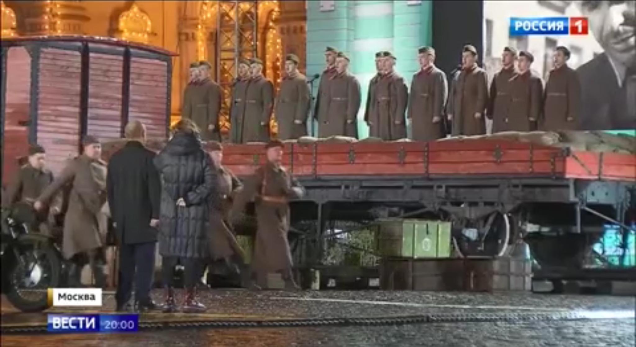 Puto stoi przed szeregiem maszerujących i śpiewających żołnierzy