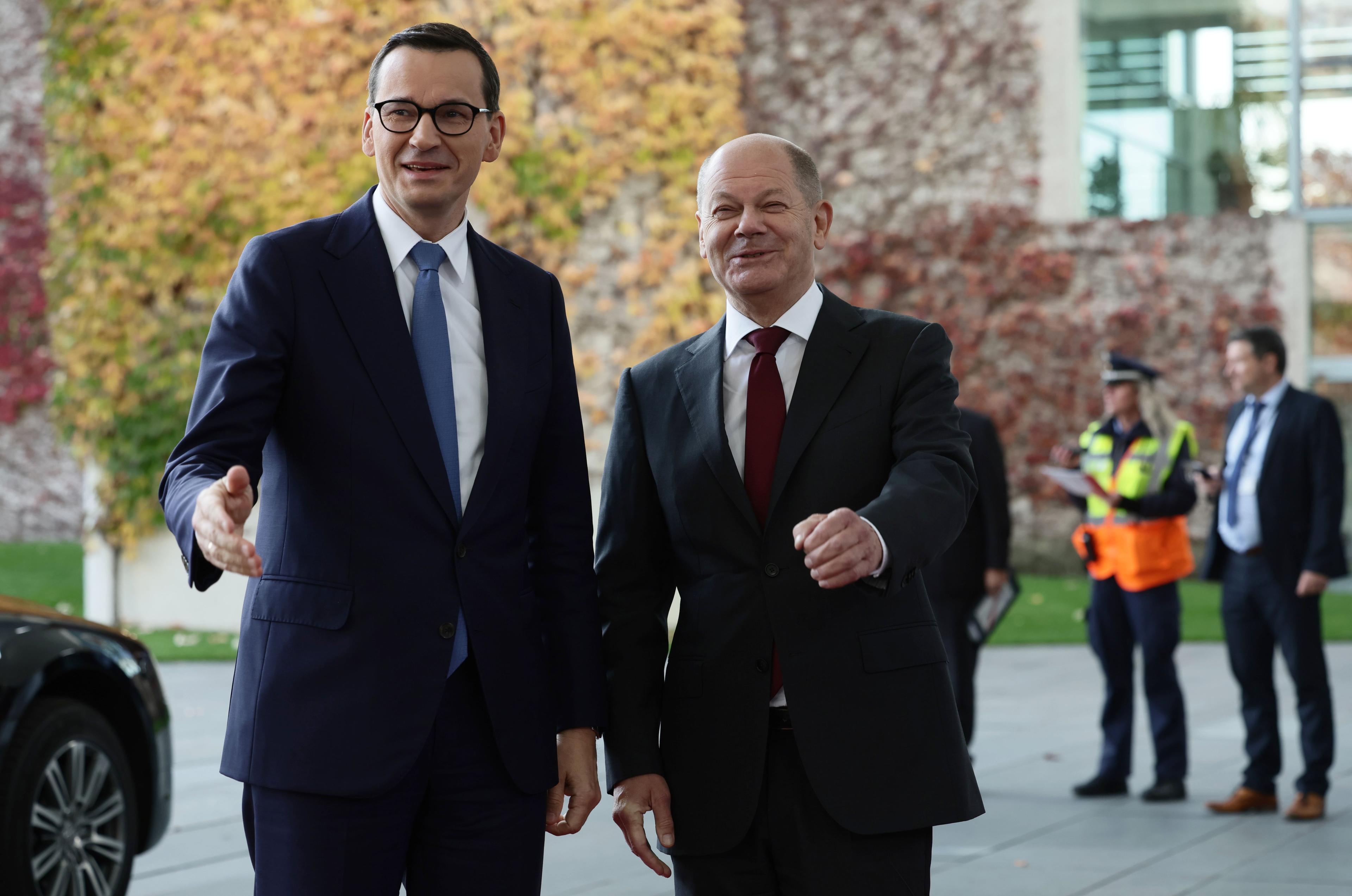 Premier Polski Mateusz Morawiecki i kanlcerz Niemiec Olaf Scholz stoją obok siebie na tle jesiennych drzew