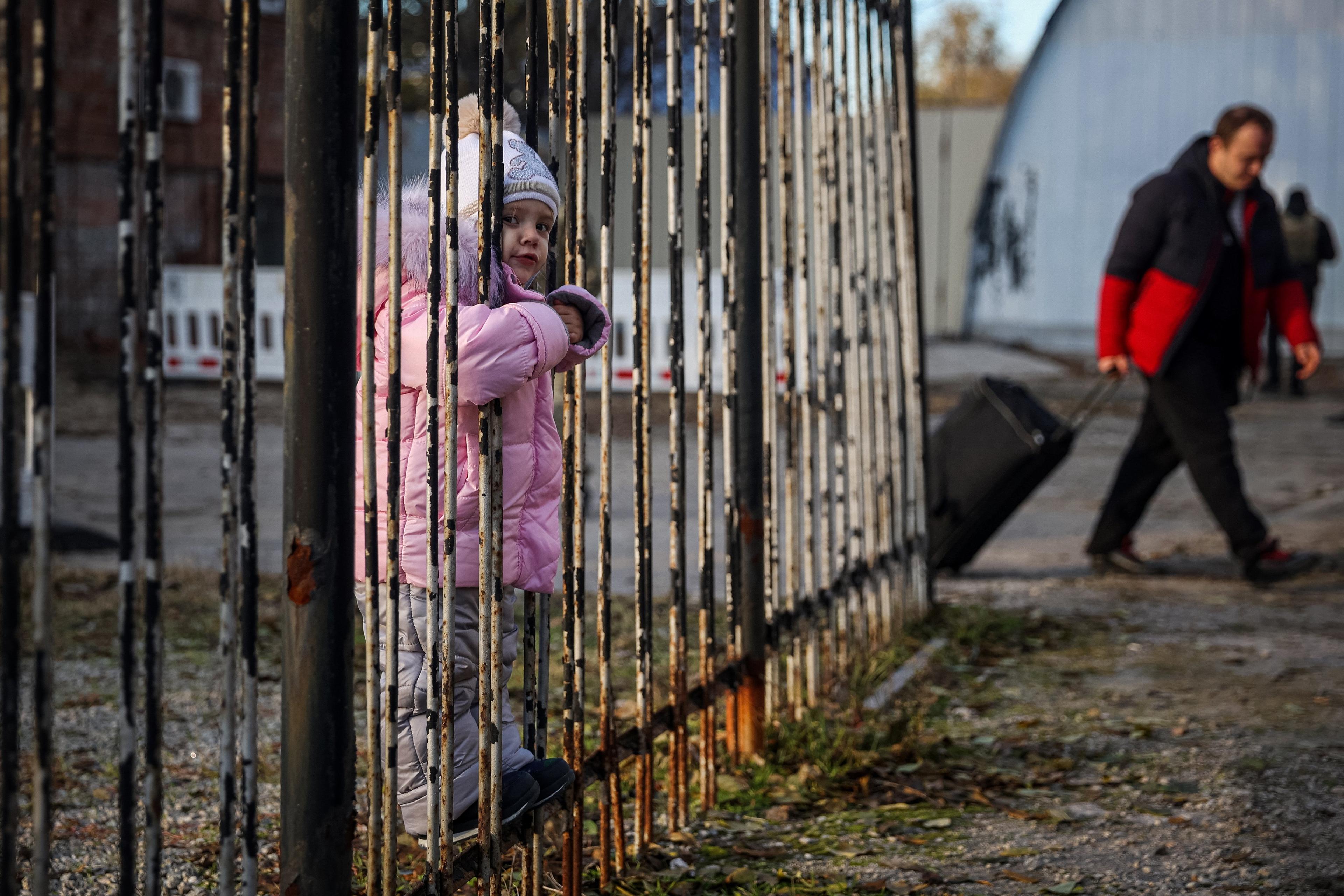 A child looks through a fence as war-displaced Ukrainians arrive from the Russian-held town of Berdyansk, at a humanitarian relief centre in the central Ukrainian city of Zaporizhzhia on November 7, 2022, amid the Russian military invasion on Ukraine. - Psychiatrists at the humanitarian relief centre prepare to receive those displaced by war, offering them immediate counselling and further guidance. (Photo by ANATOLII STEPANOV / AFP)